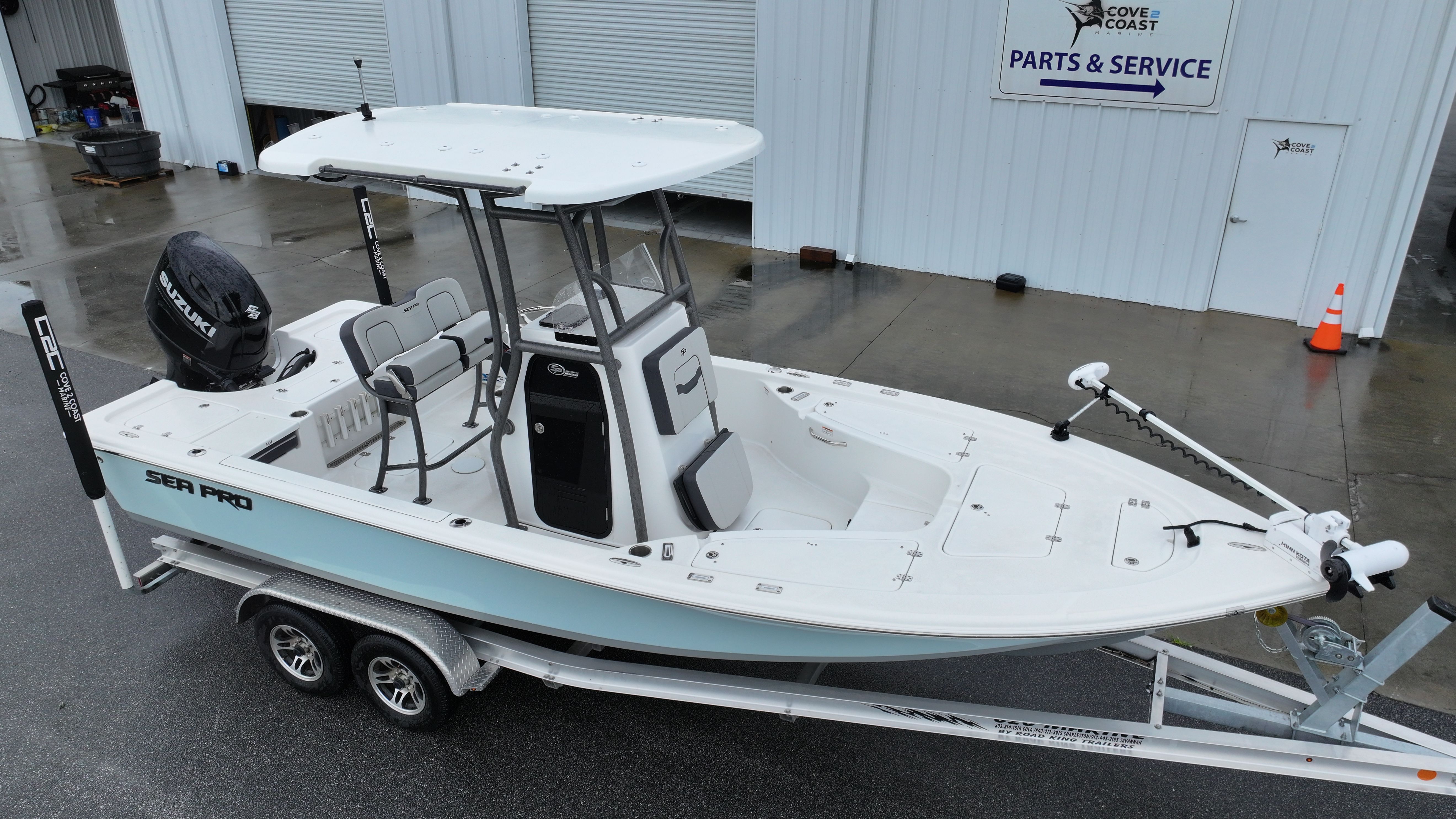 A 2025 Sea Pro 230 DLX boat on a trailer in front of a workshop.