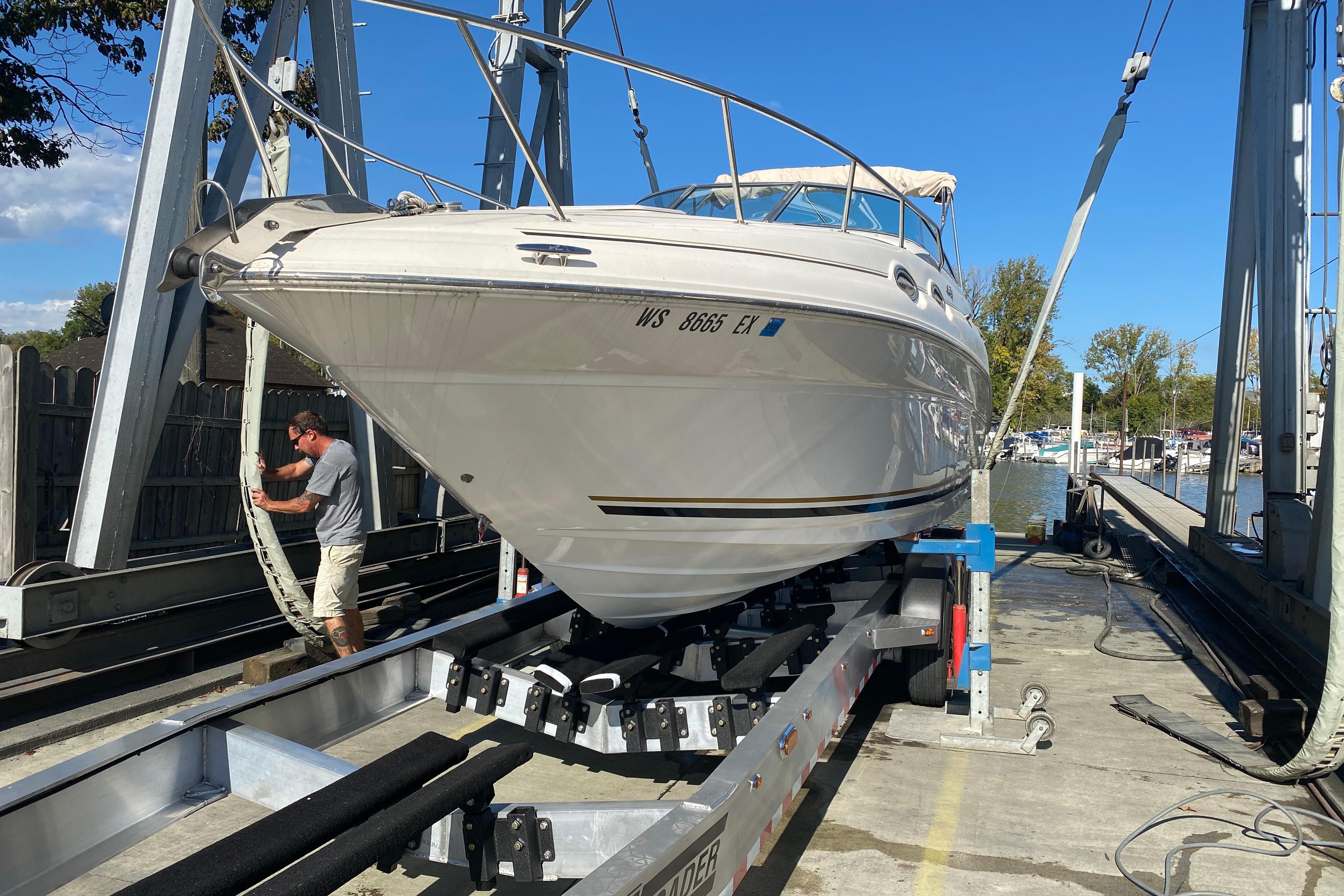 2001 Sea Ray Sundancer 260 on trailer at marina, man securing boat.