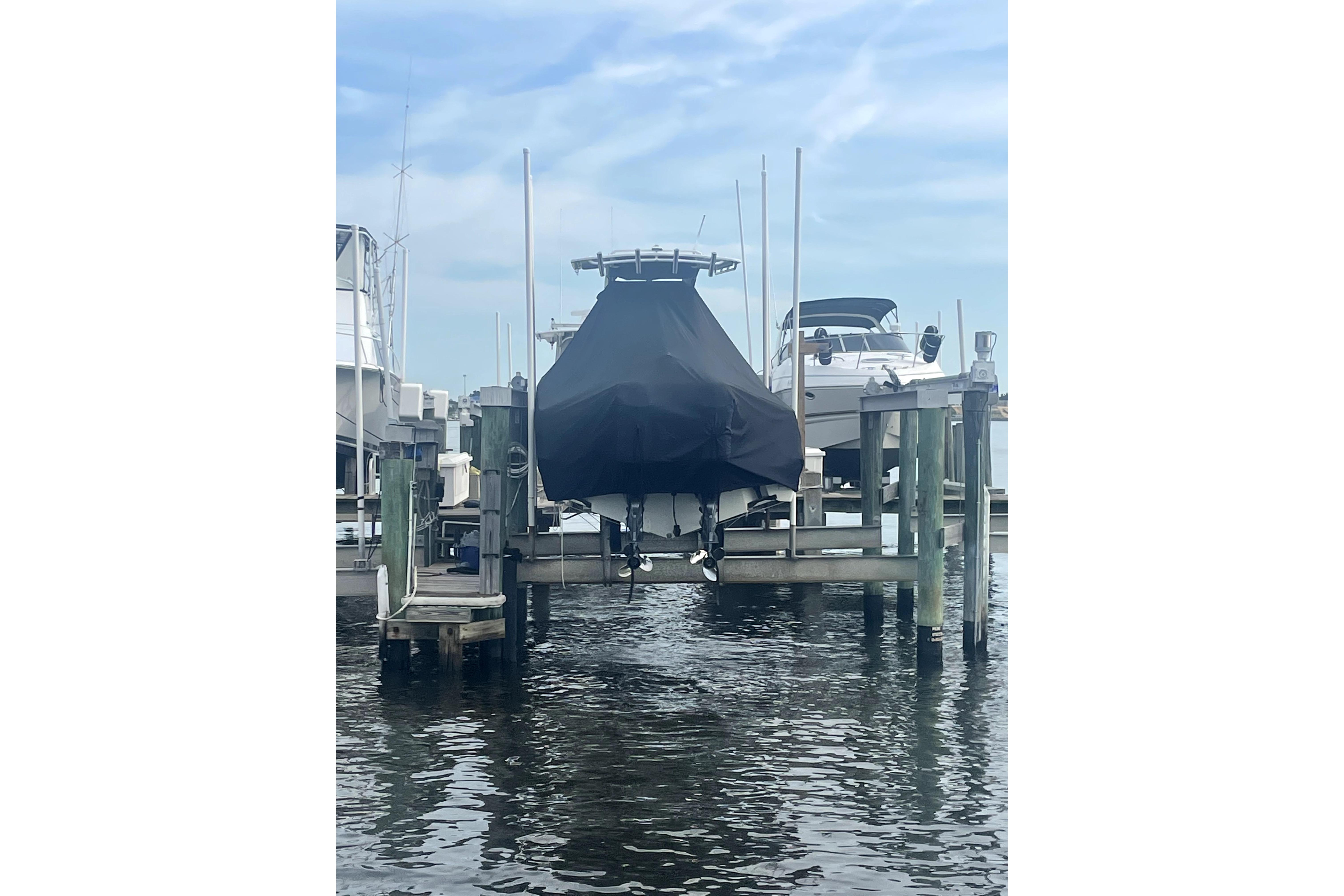 Covered 2015 Edgewater 245CC boat on a lift at a marina.