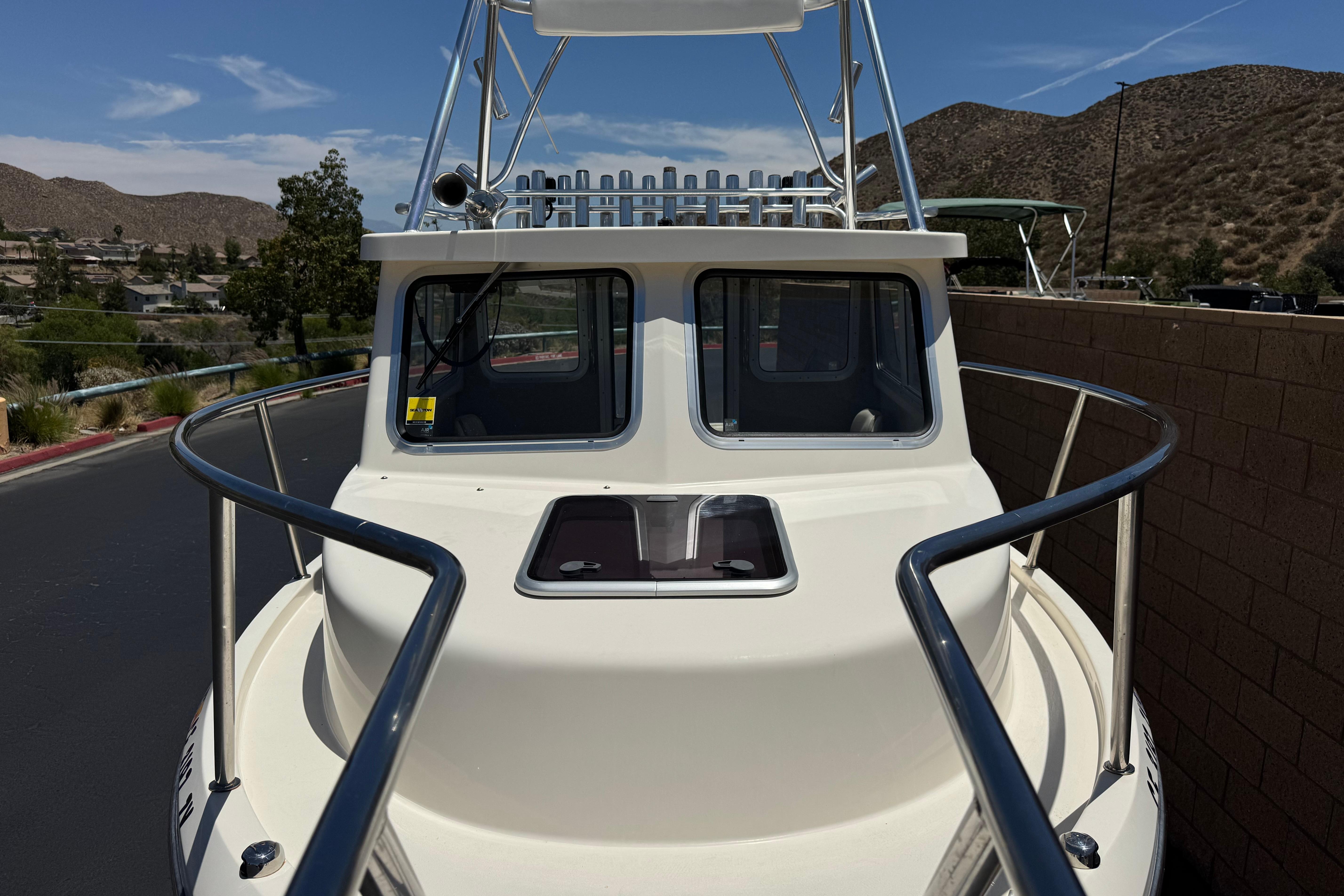 2017 Defiance Admiral 220 EX boat with white exterior, docked near a scenic mountainous area.