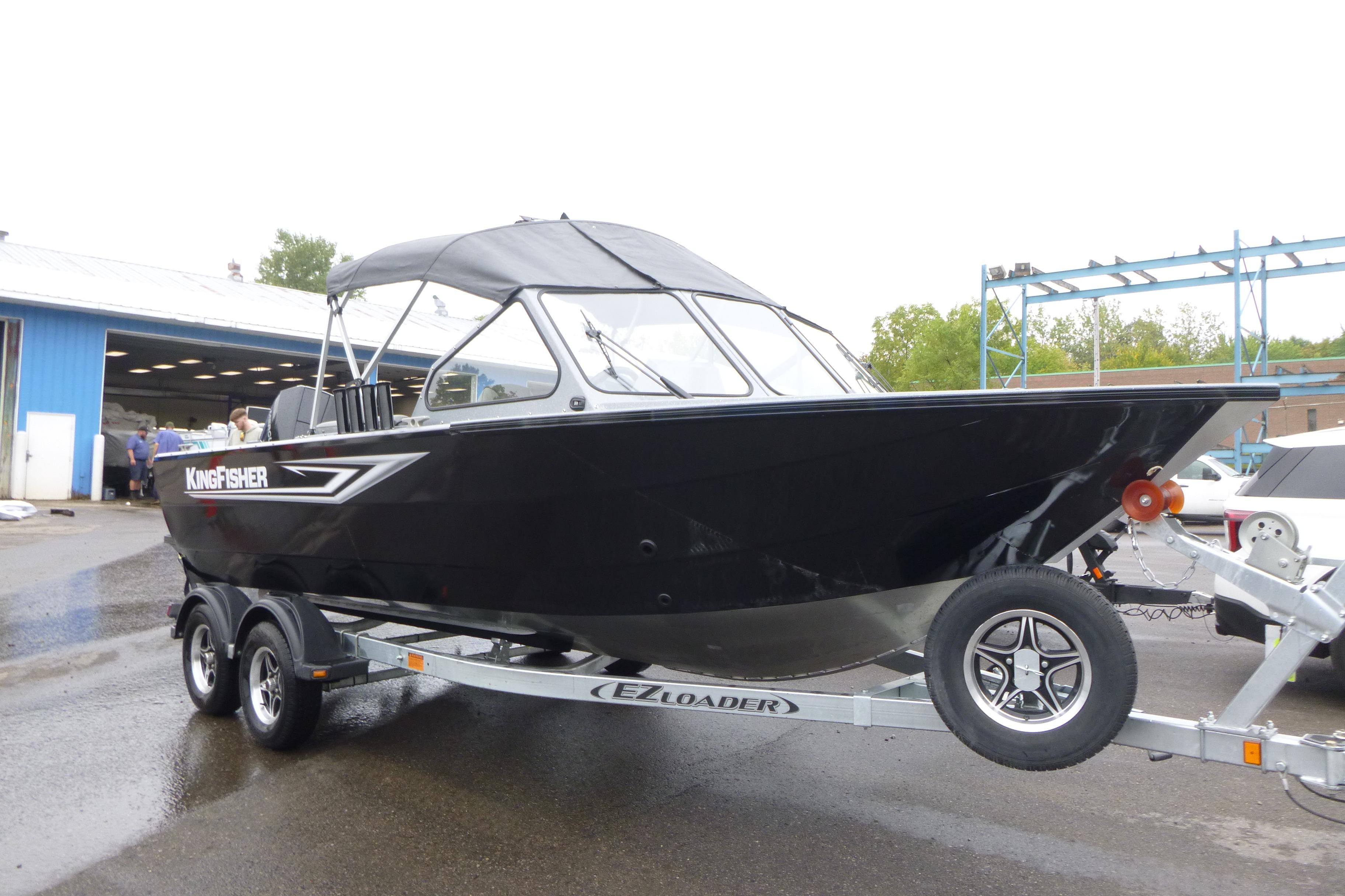 2026 KingFisher 2025 Escape boat on trailer, parked outdoors near a blue building.