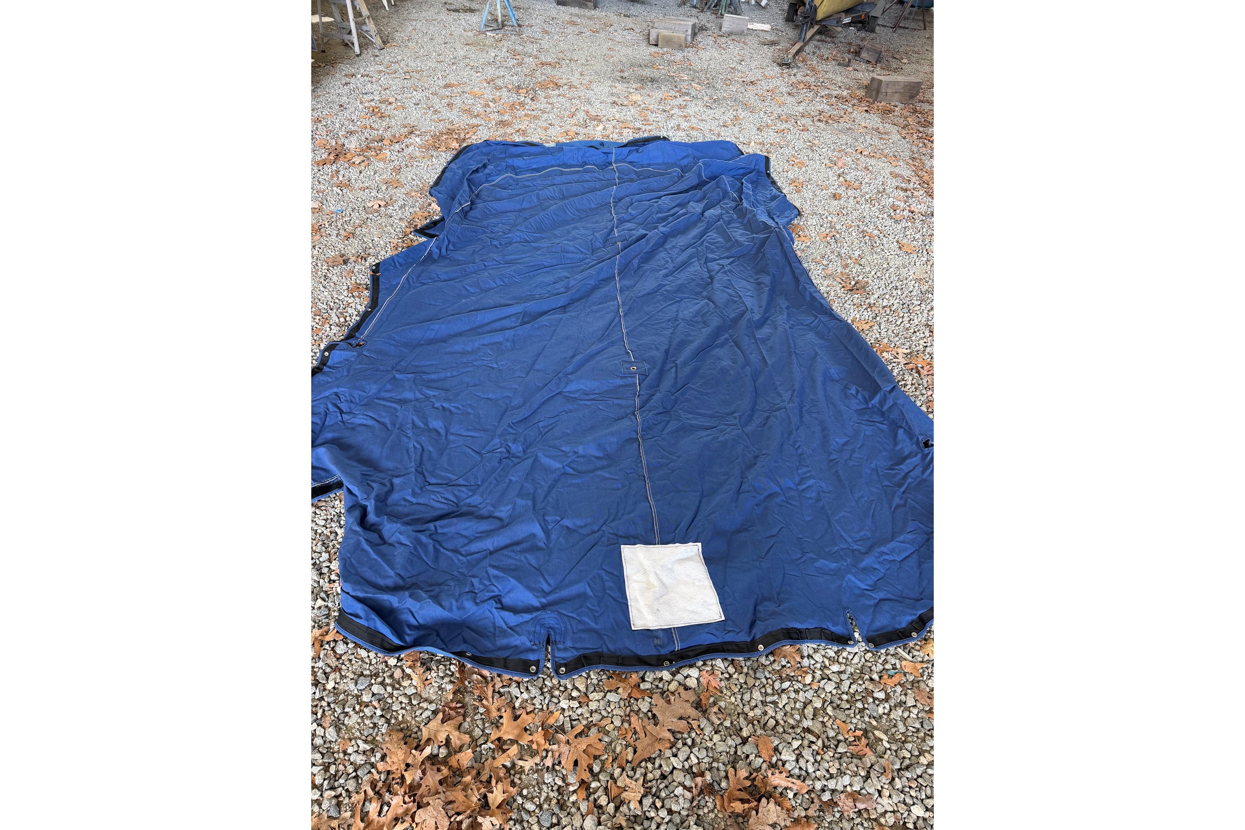 Blue boat cover for 2000 Sea Ray 240 Sundancer on gravel with autumn leaves.