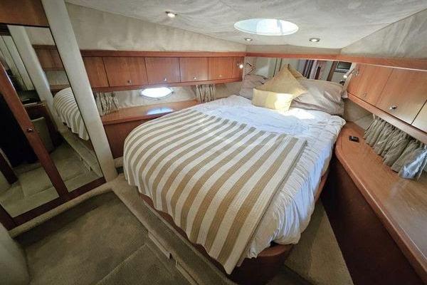 Luxurious cabin interior of 2005 Sunseeker Manhattan 66 yacht with cozy bed and wood paneling.