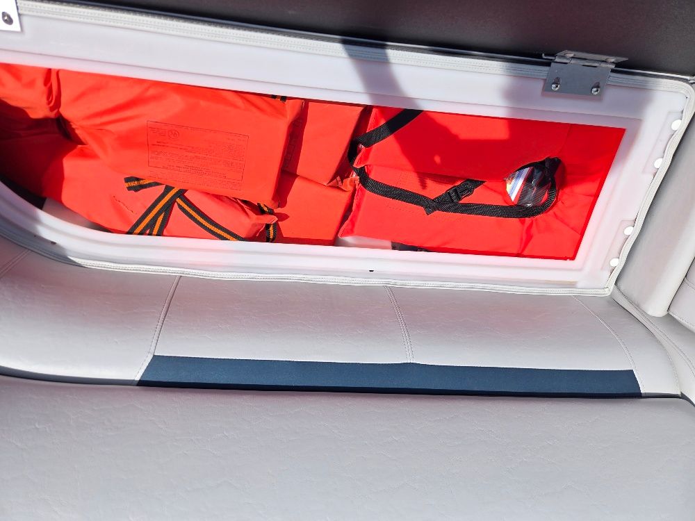 A storage compartment on a boat with orange life jackets.