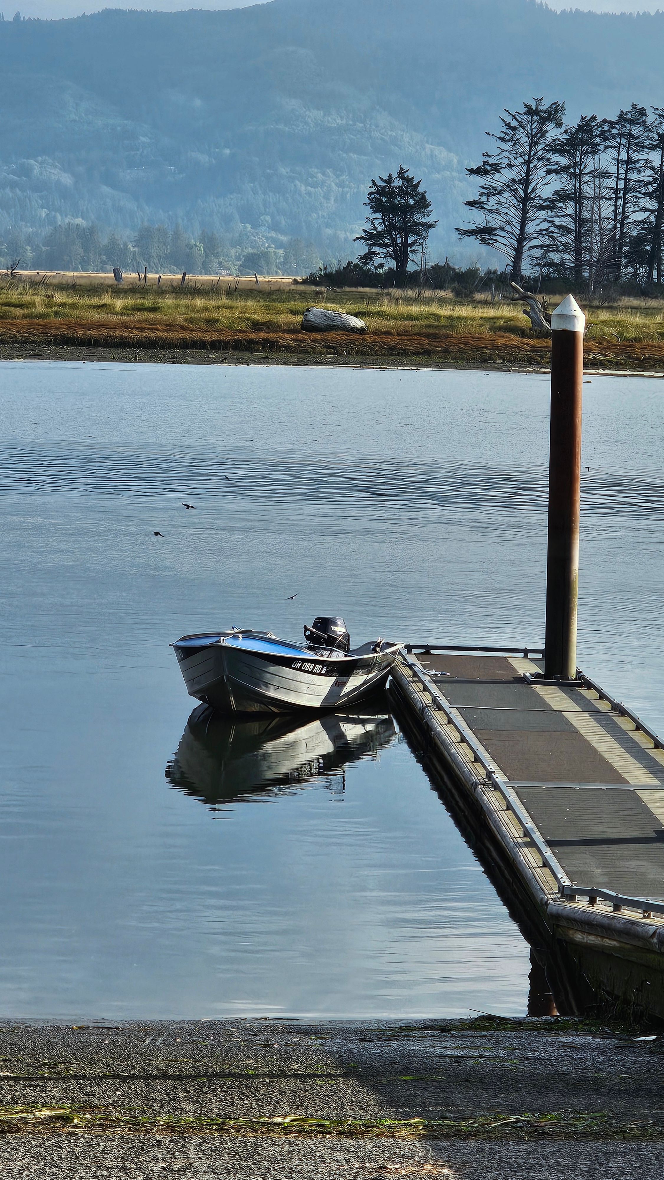 A 1988 aluminum fishing boat is moored at a dock on calm water.