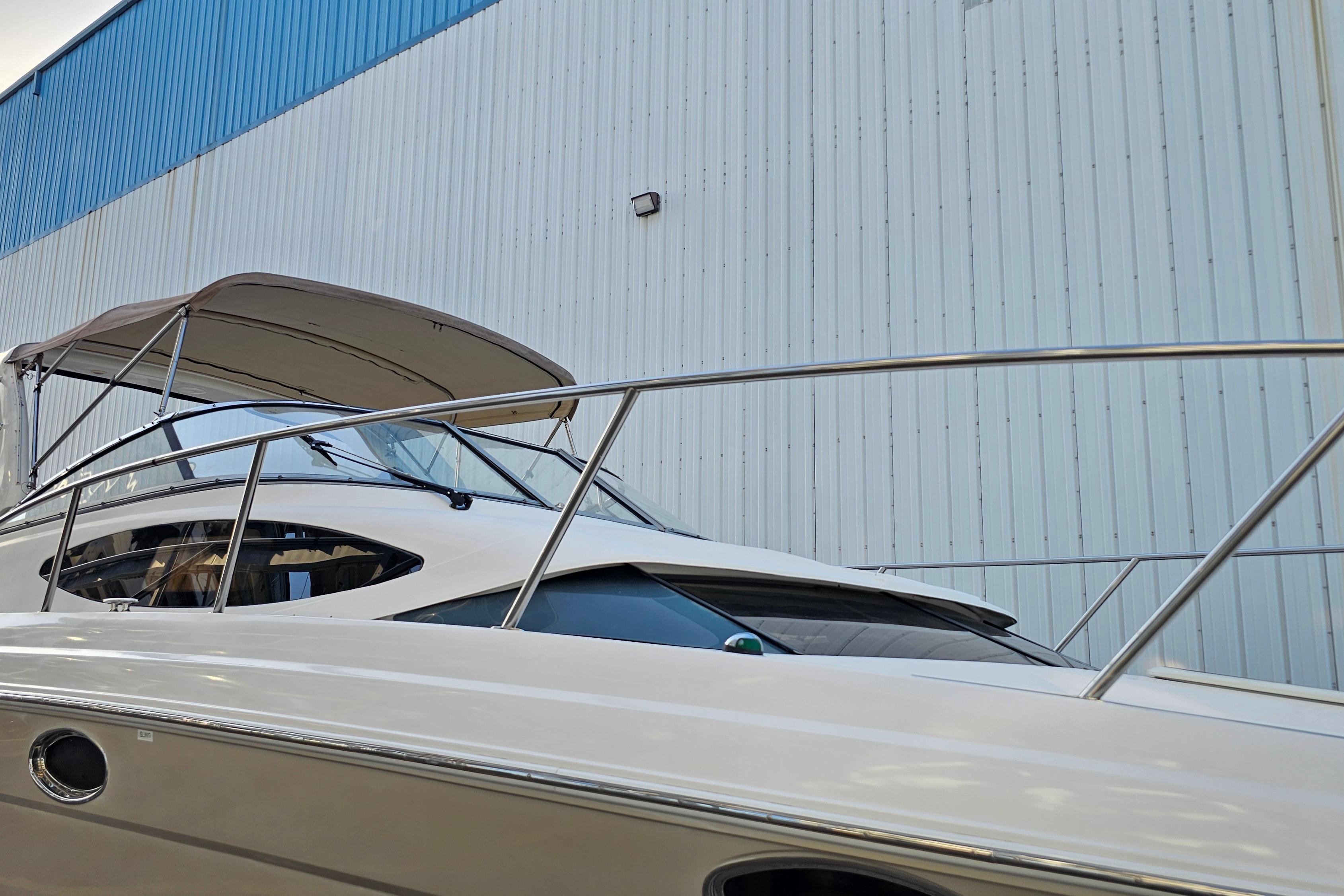 2005 Regal 3060 Window Express boat docked near a large warehouse.