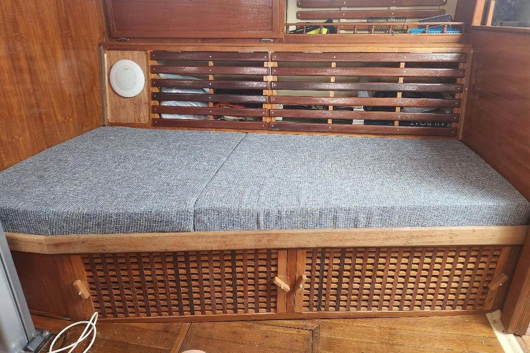 Interior of 1984 Bayfield 32C sailboat with wooden bench and gray cushion.
