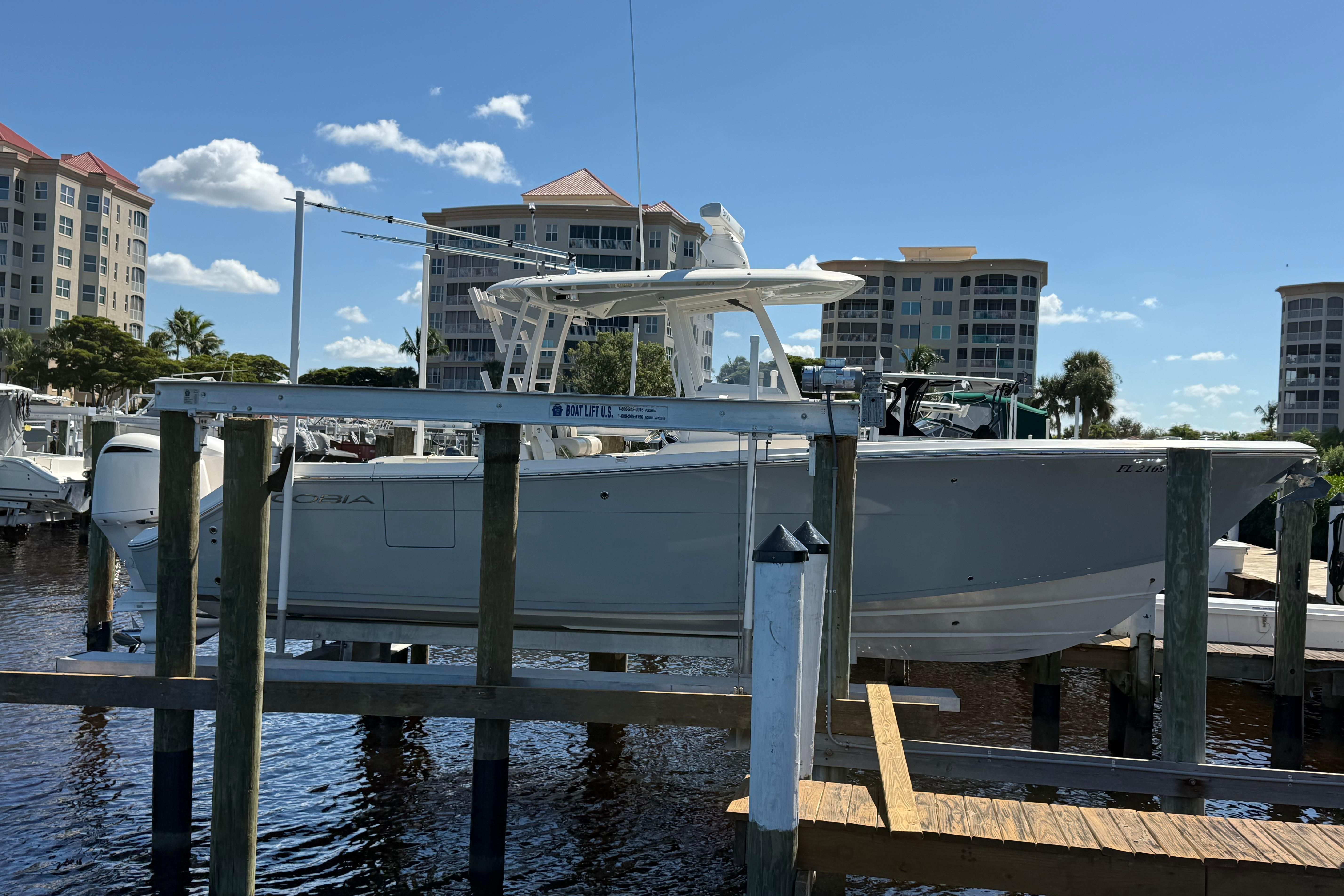 2018 Cobia 301 Center Console boat docked at marina with buildings in background.