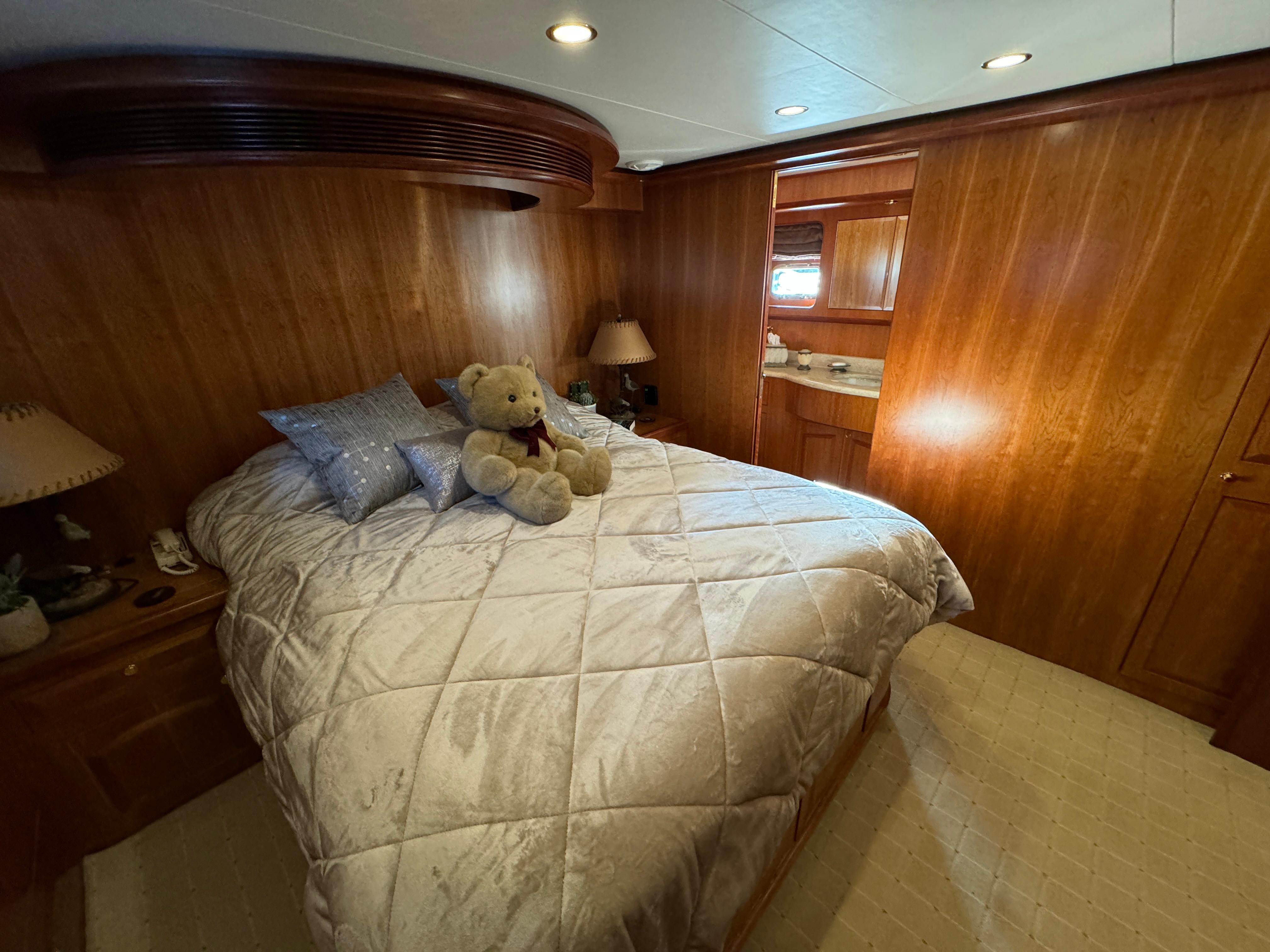 Luxurious bedroom in 2006 President 63 Pilot House yacht with plush bedding and wooden interior.