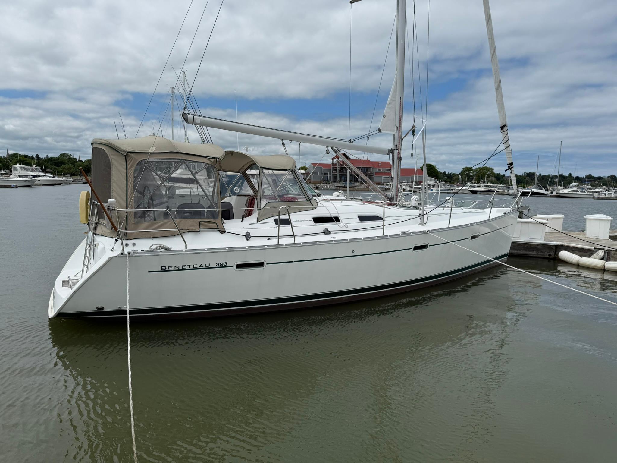 2003 Beneteau 393 sailboat docked in a marina under cloudy skies.