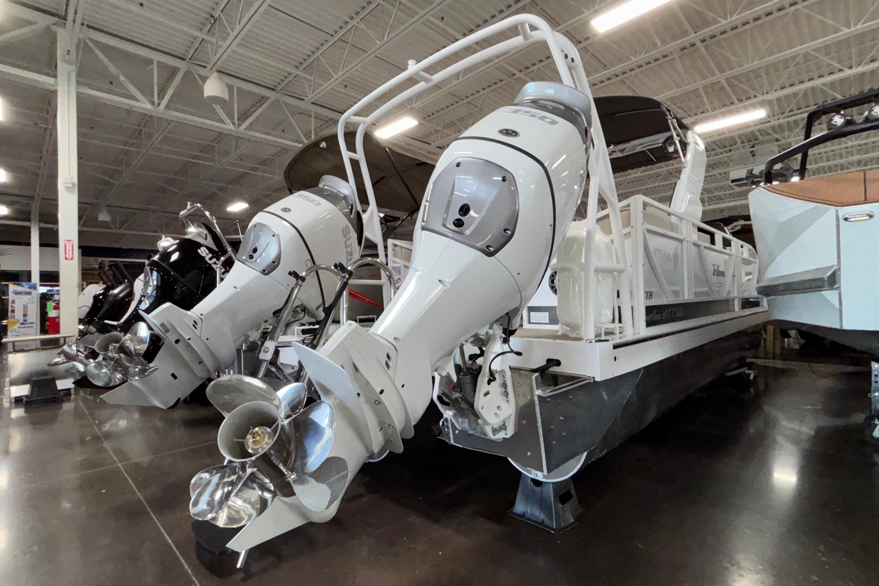 2026 JC Sporttoon 26TT pontoon boat with dual outboard motors in a showroom.