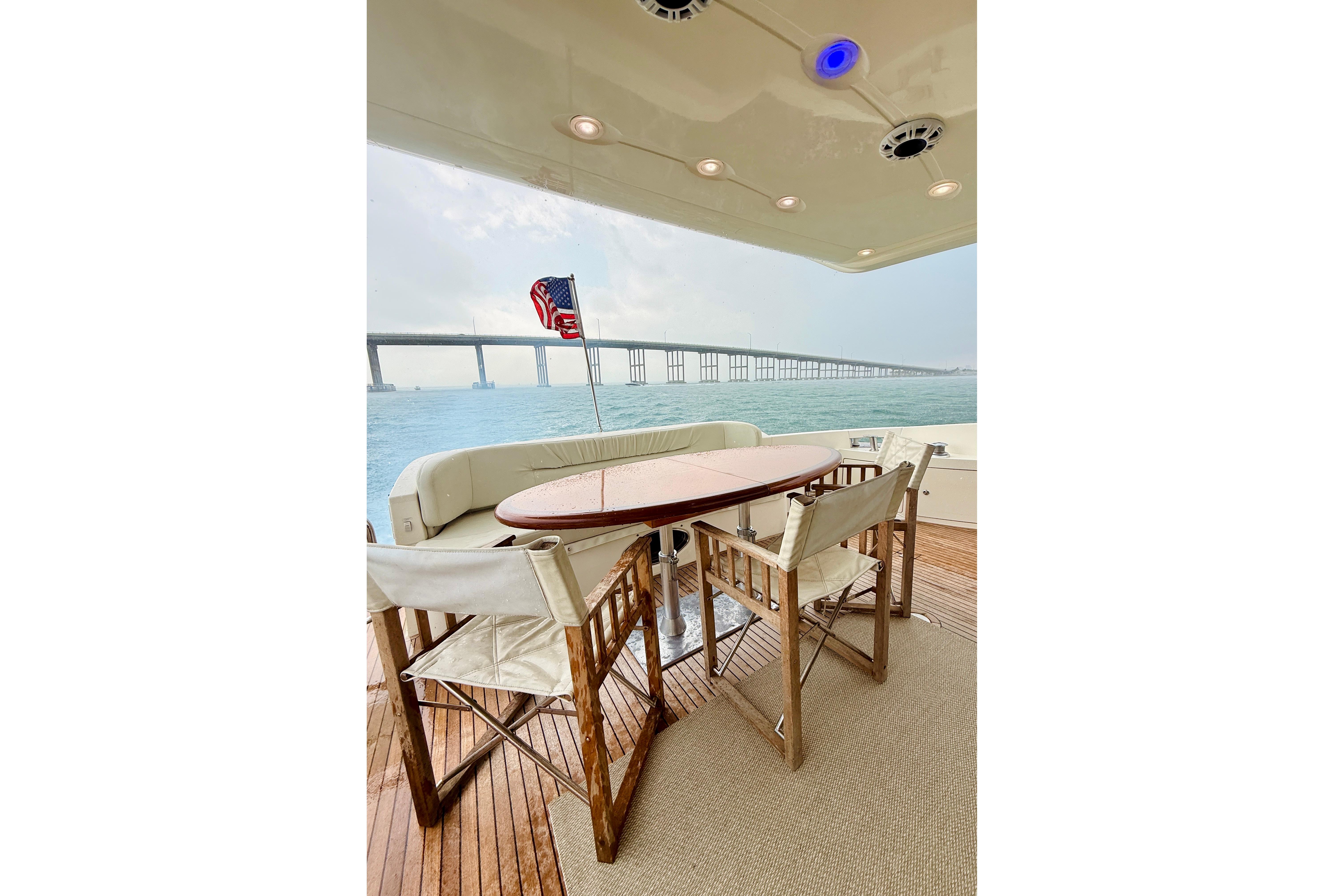 Outdoor seating on 2007 Azimut 68E yacht with ocean view and bridge in background.