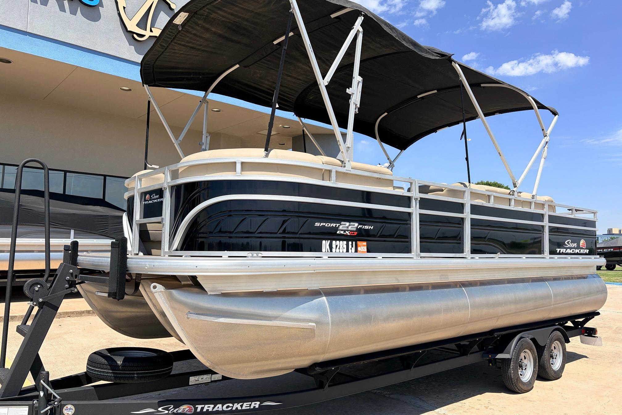 2024 Sun Tracker SportFish 22 XP3 pontoon boat on trailer, displayed outdoors.