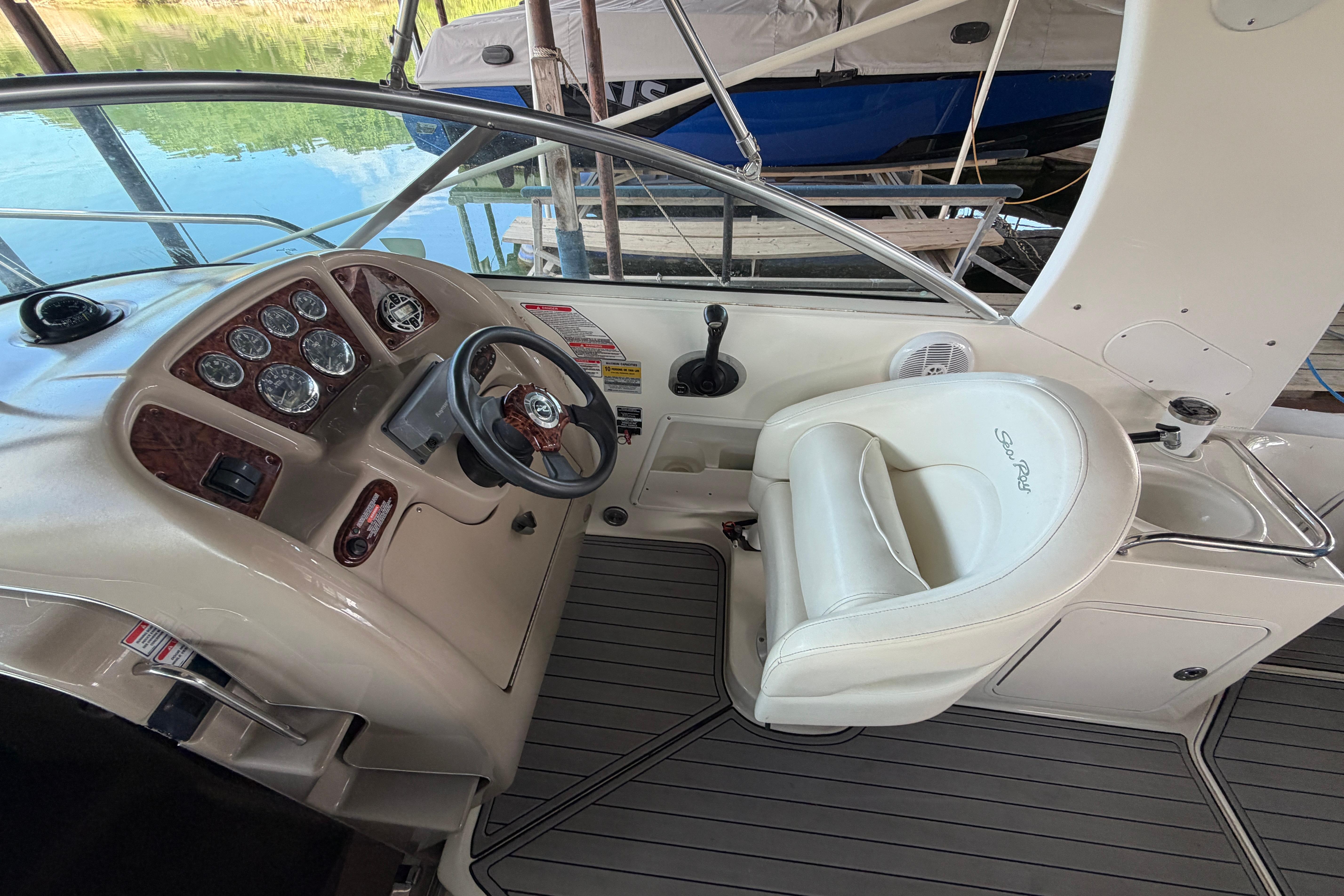 2004 Sea Ray Sundancer 260 helm with steering wheel and gauges, featuring a white captain's chair.