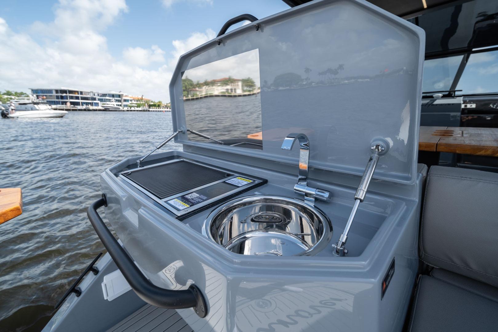 Outdoor kitchen on Hanover 387 boat, featuring sink and grill, with waterfront view.
