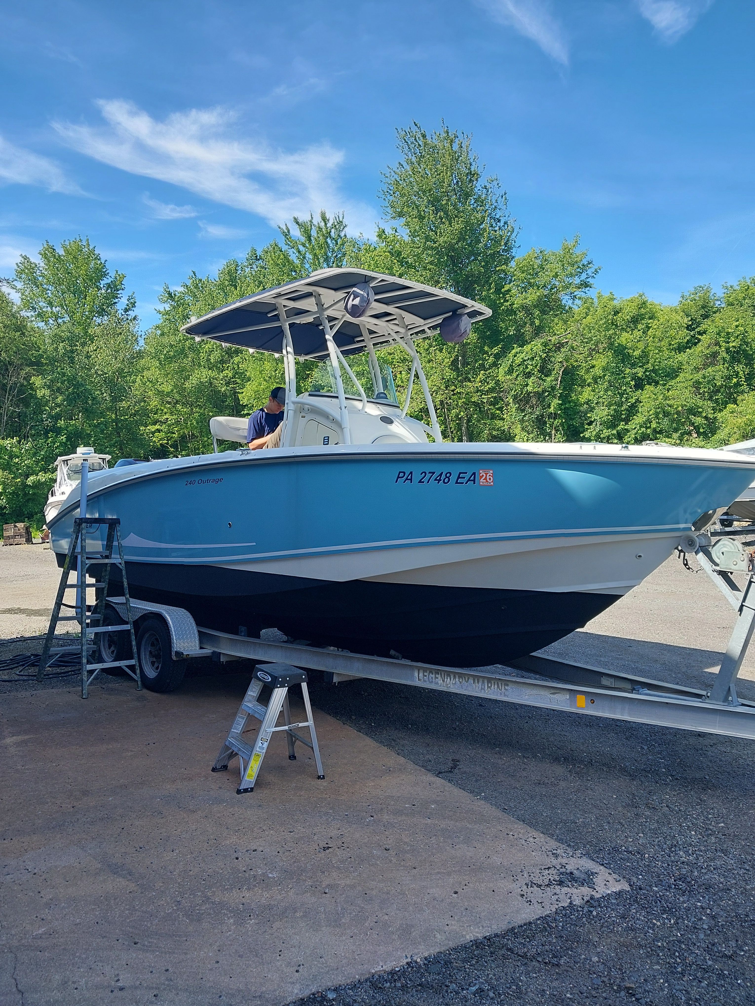 A 2005 Boston Whaler 240 Outrage on a trailer, surrounded by trees.