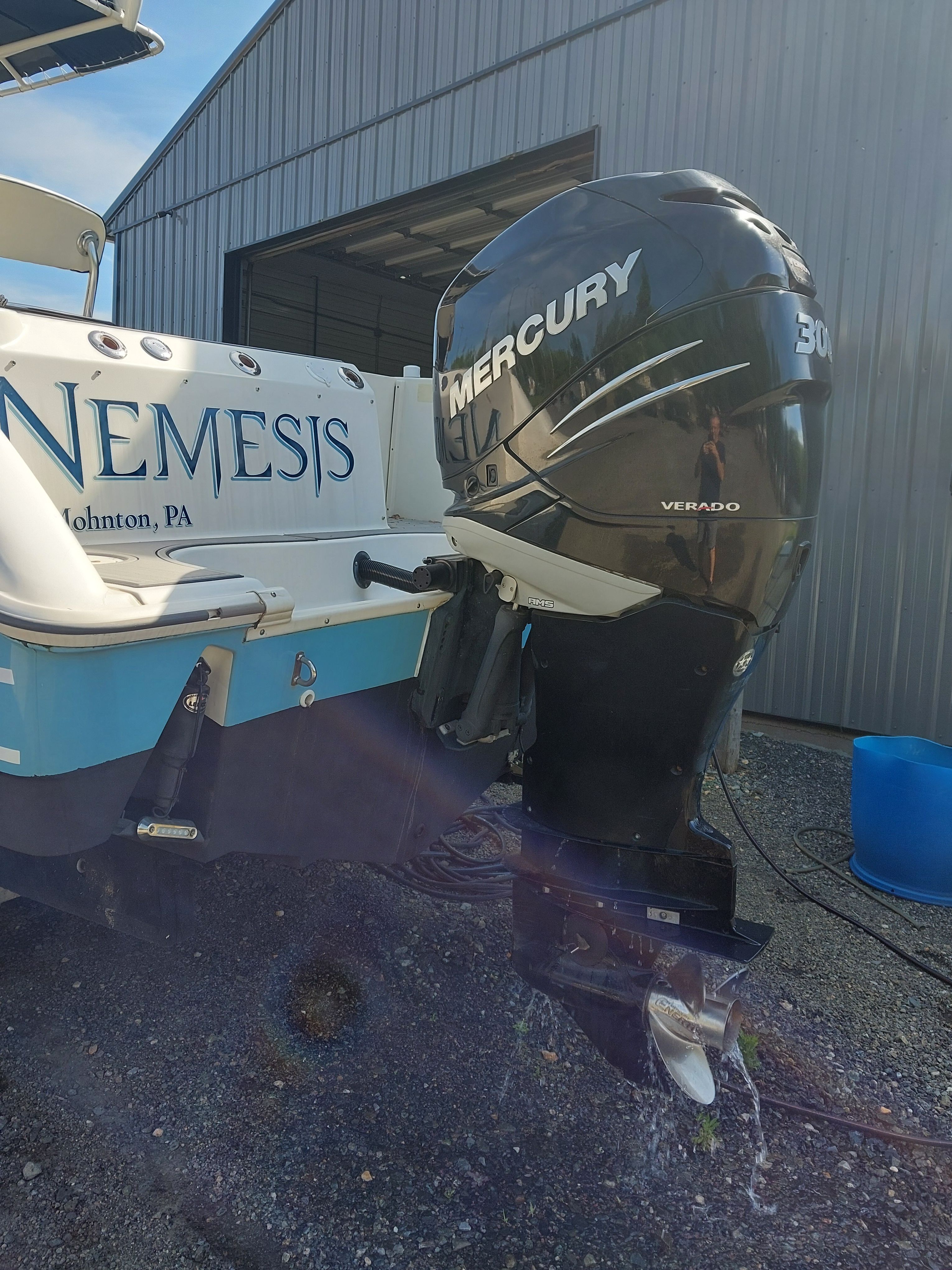A 2005 Boston Whaler 240 Outrage with a Mercury outboard motor, parked beside a building.