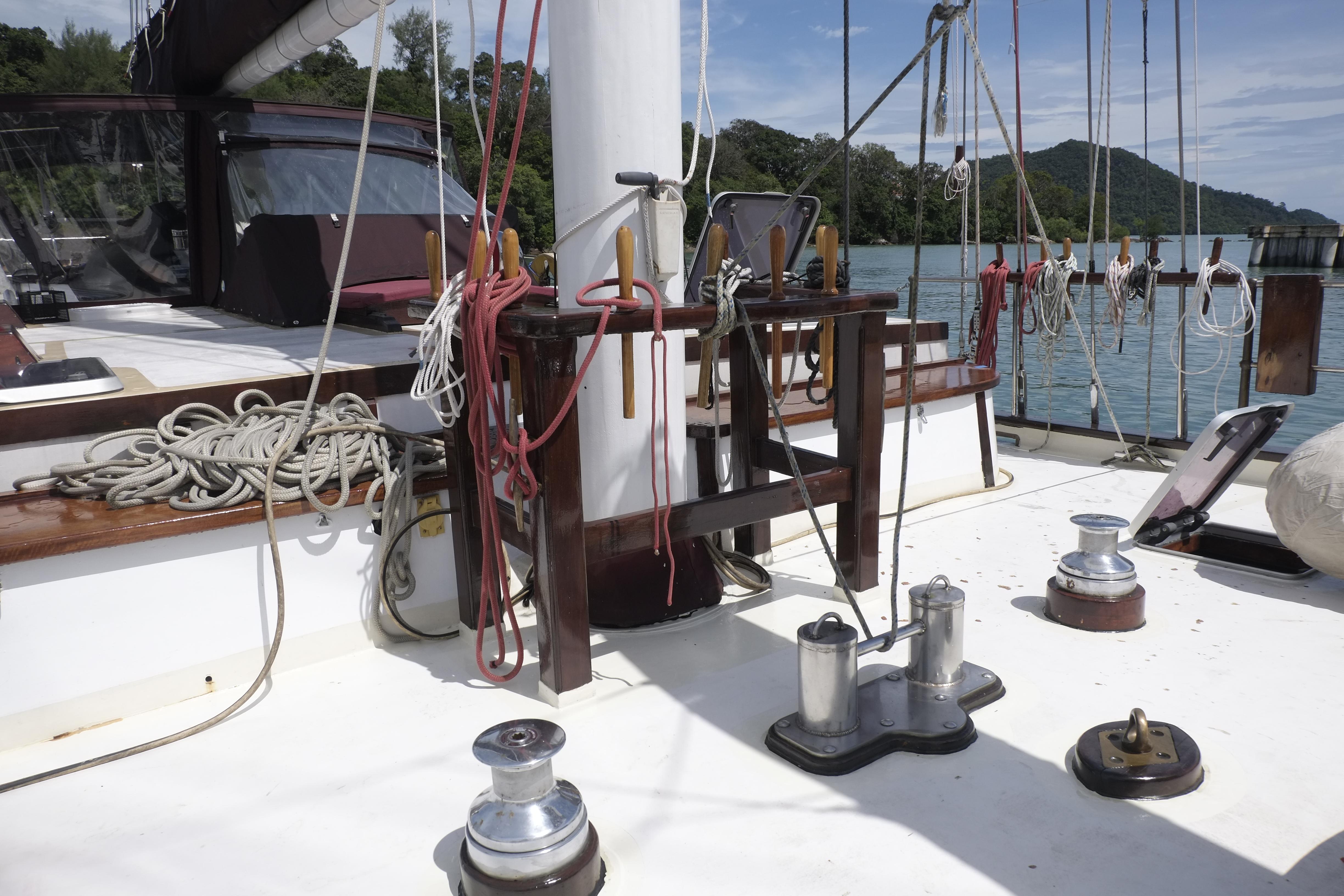 Deck of 2006 Custom Bud Macintosh schooner with ropes and winches, docked by lush shoreline.