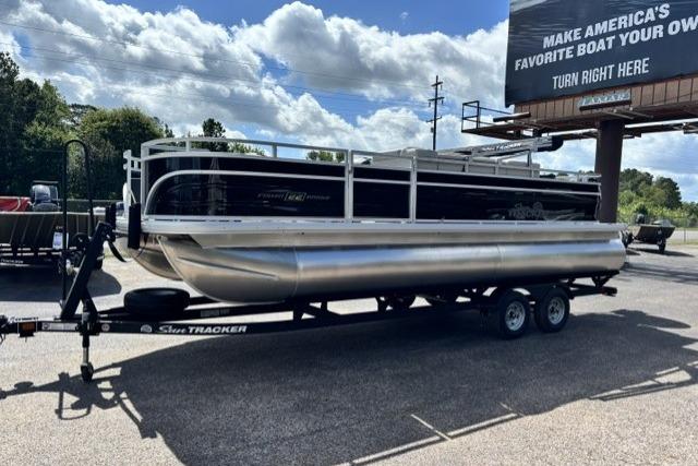 2026 Sun Tracker Fishin' Barge 22 DLX pontoon boat on trailer, outdoor display.