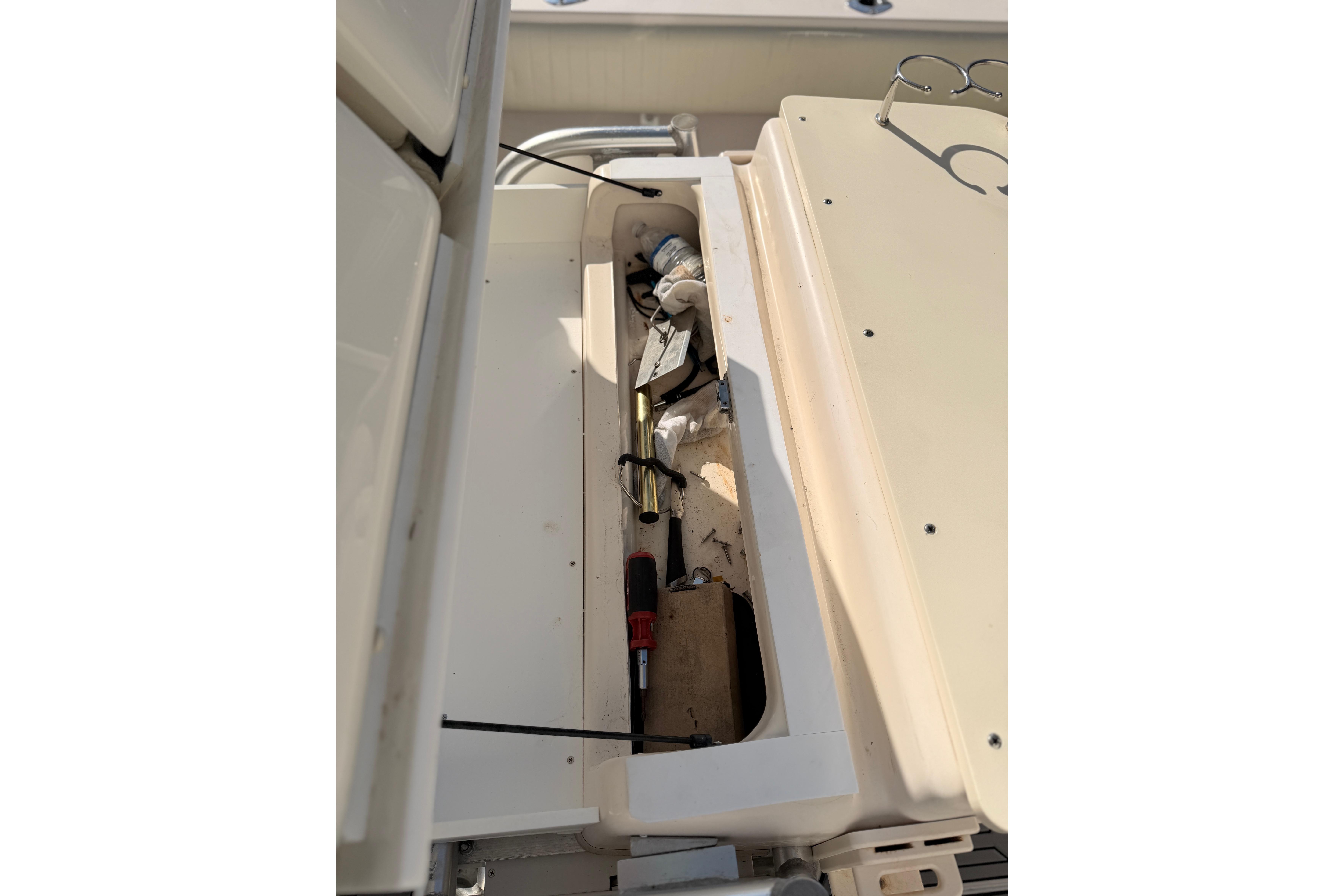 Open storage compartment on 2004 Grady White 273 boat with tools and equipment.
