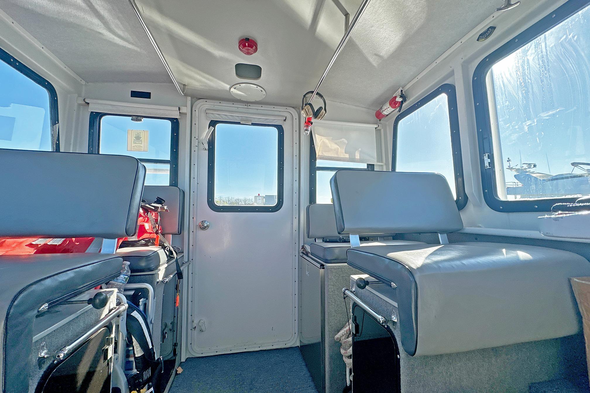 Interior of a 1990 Boston Whaler 36 Defiance boat, featuring seating and windows.