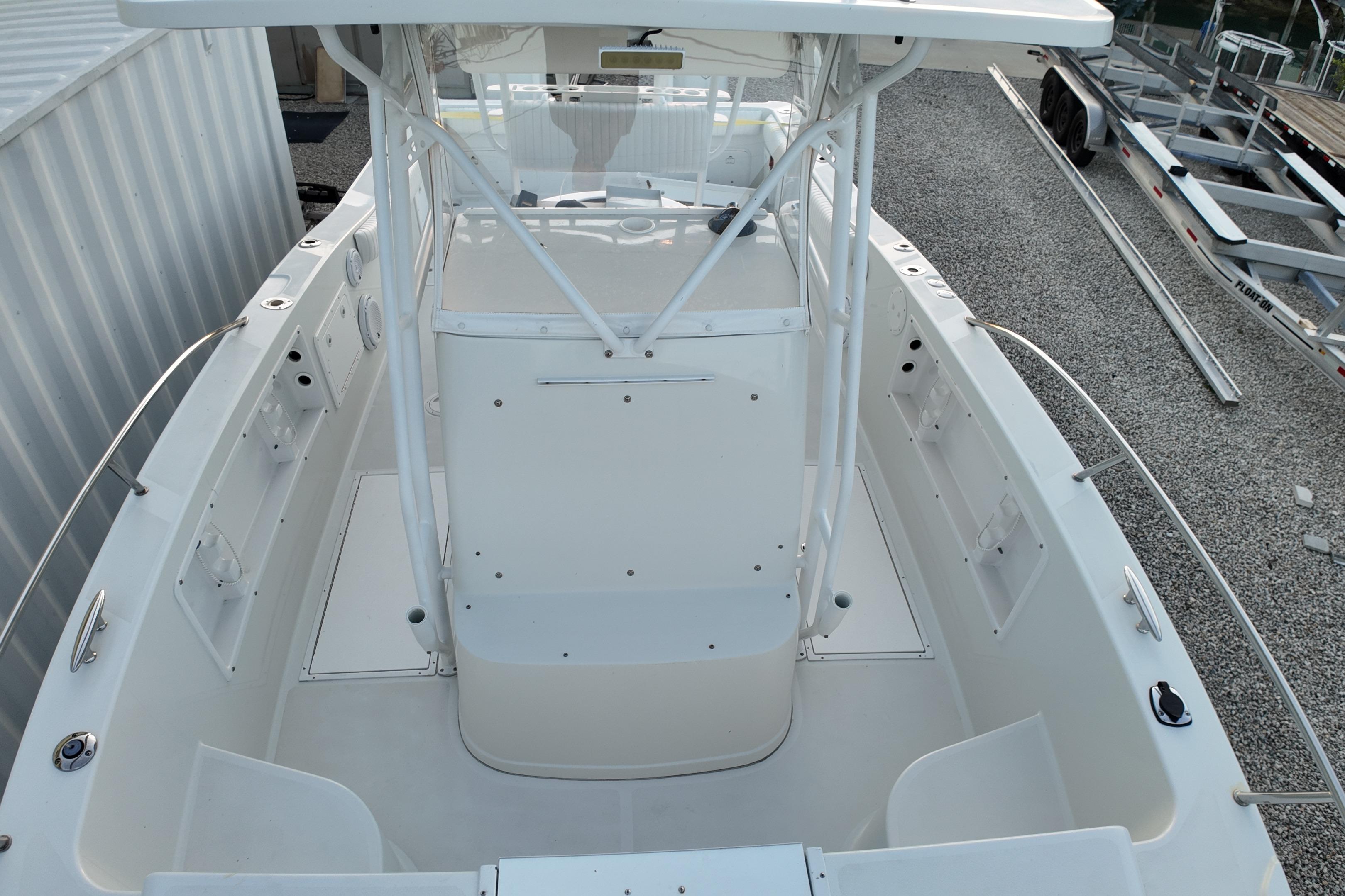 2003 Pro Sports 2860 SC ProKat boat, white deck, center console, docked on gravel.