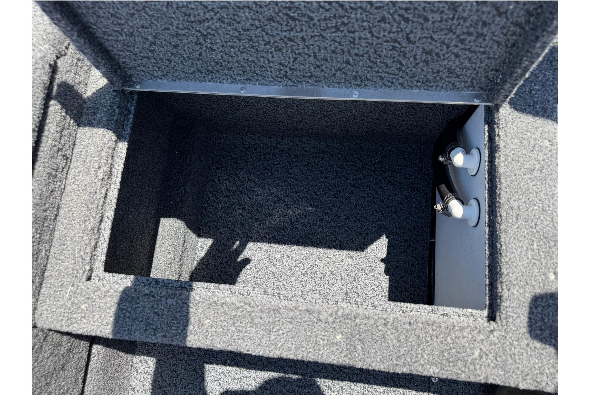 Open storage compartment in 2027 Lund 1875 Pro Guide boat, featuring carpeted interior.