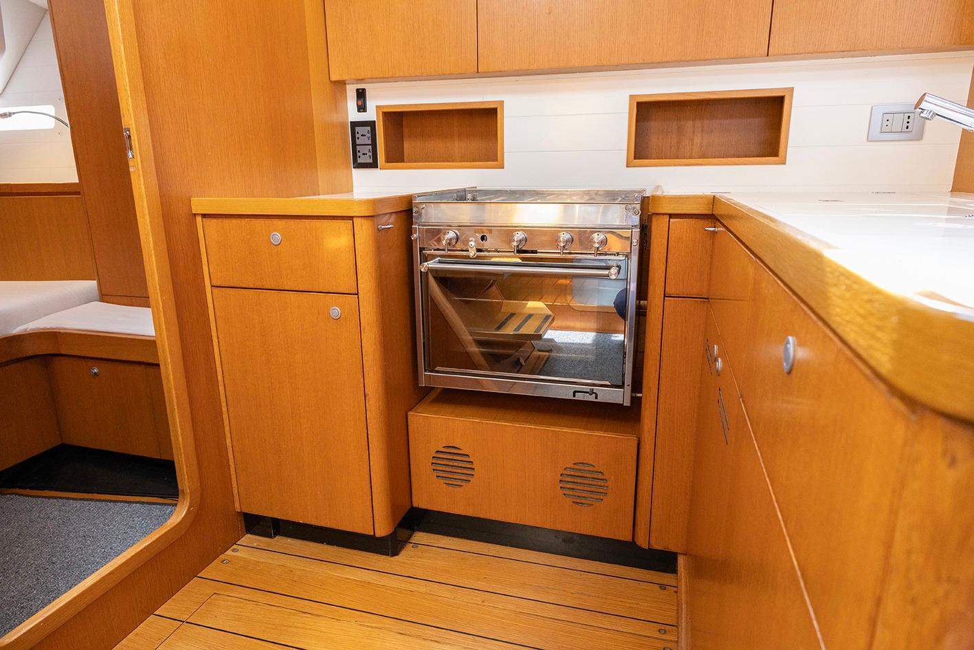 Grand Soleil 46 yacht kitchen interior, featuring wooden cabinetry and a stainless steel oven, 2010 model.