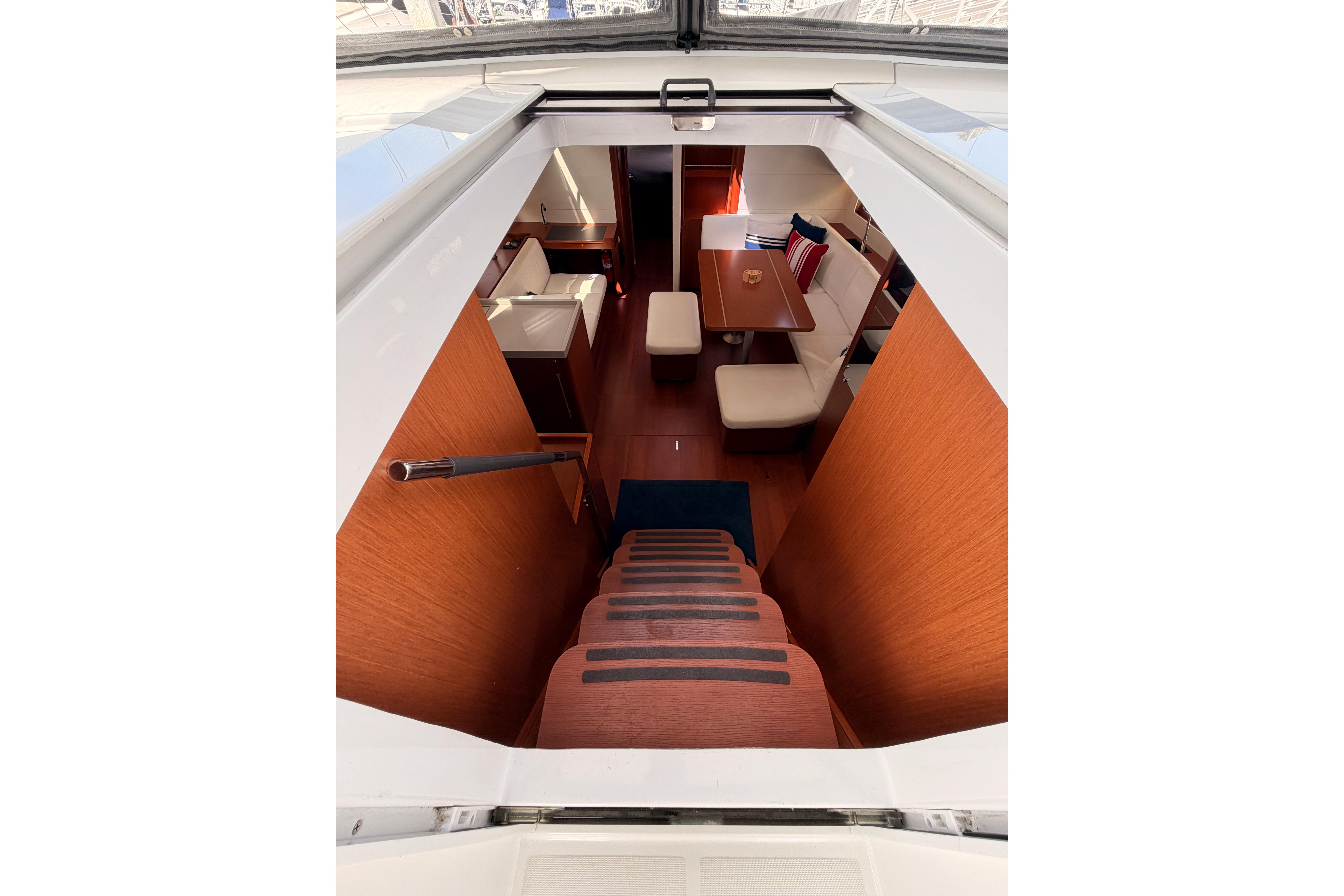 Interior view of 2020 Beneteau Oceanis 46.1 yacht, featuring elegant wooden stairs and cozy seating area.