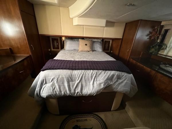 Luxurious bedroom in a 2009 Ovation 52 yacht with a cozy bed and elegant wood finishes.