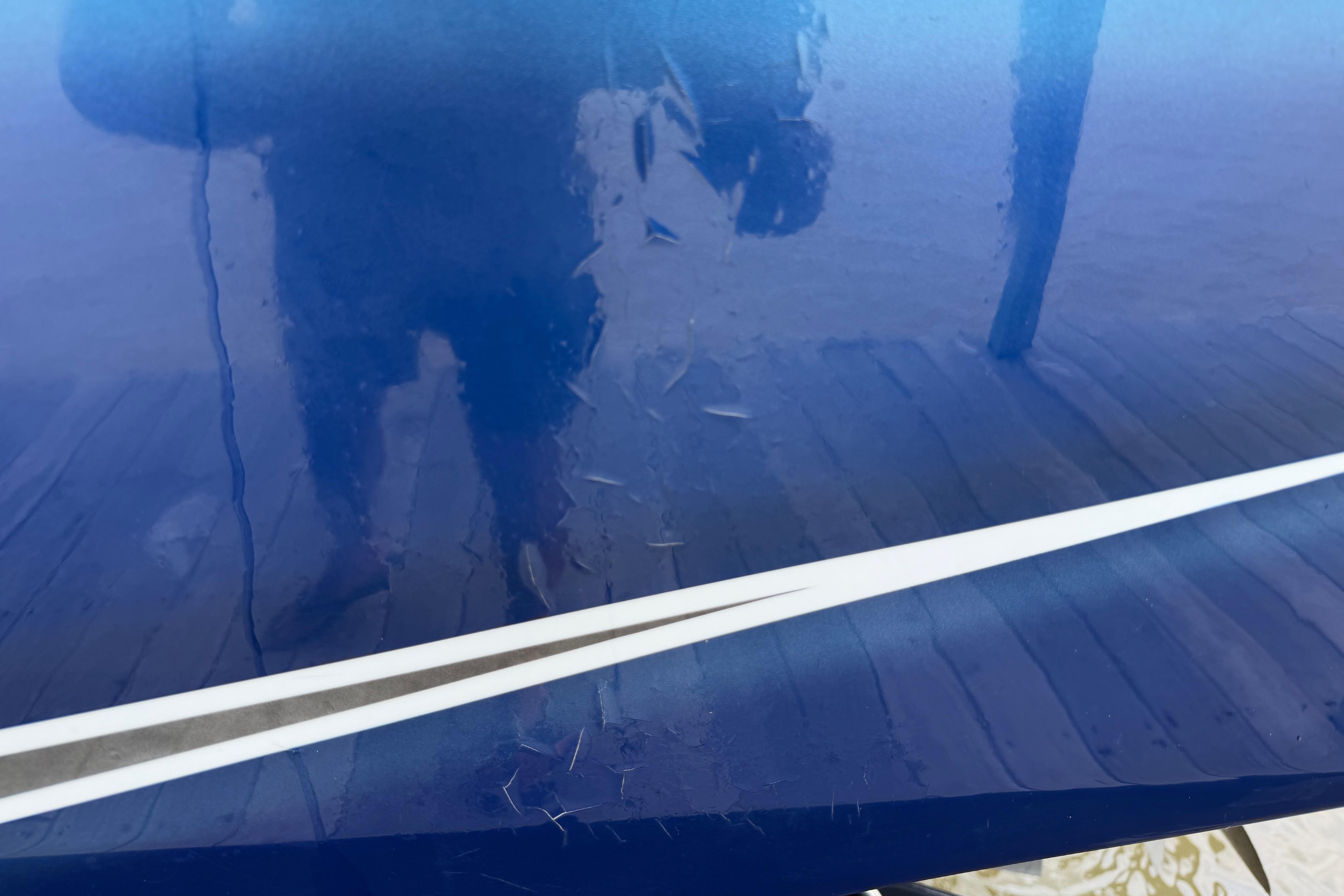 Close-up of 2013 Nor-Tech 477 SPX Vee Bottom boat with visible scratches on blue surface.