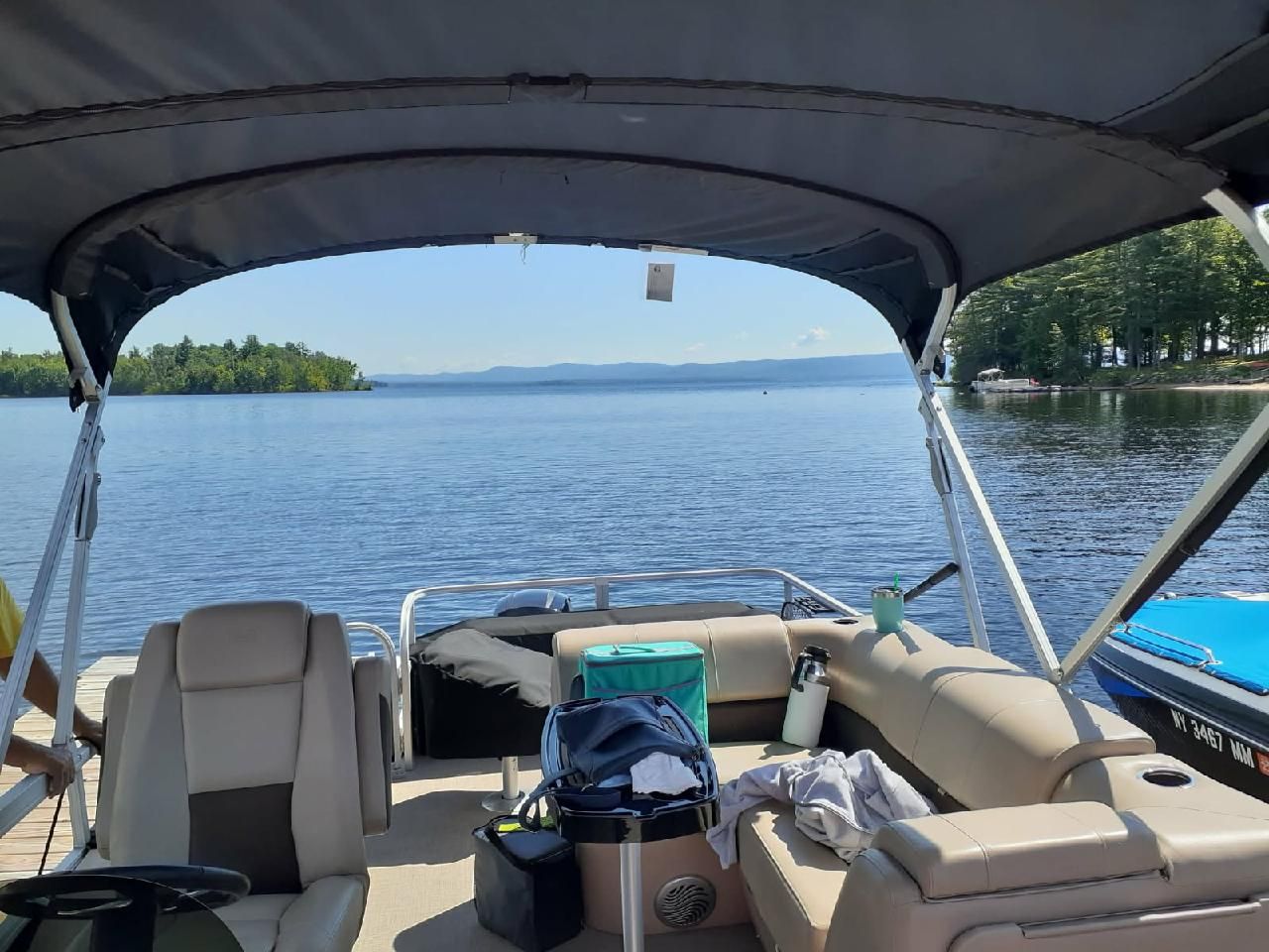 A pontoon boat with seating and luggage on a calm lake.