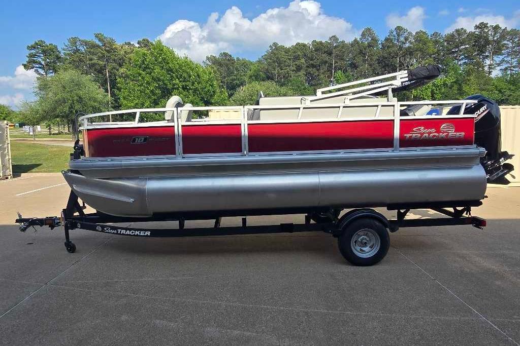 2026 Sun Tracker Bass Buggy 18 DLX pontoon boat on trailer, parked outdoors.