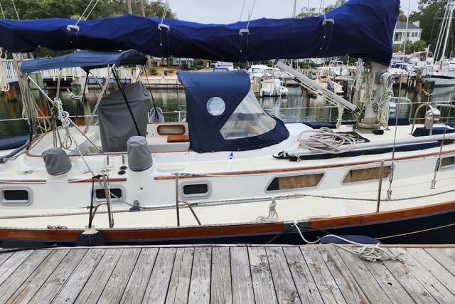 1984 Bristol 45.5 Center Cockpit sailboat docked at a marina, featuring blue canvas covers.