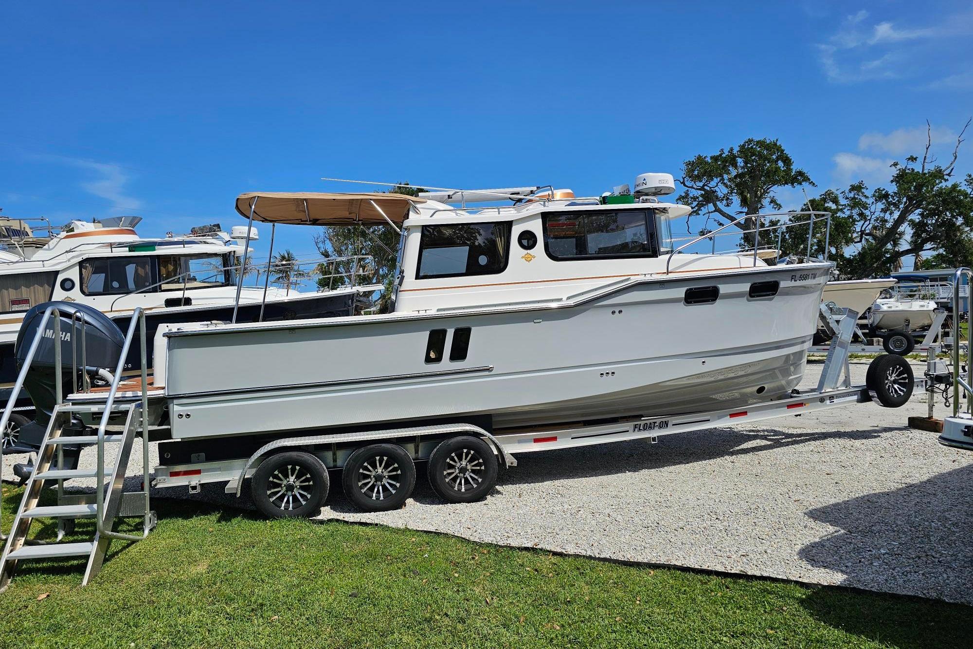 2023 Ranger Tugs boat on trailer, parked outdoors under clear blue sky.