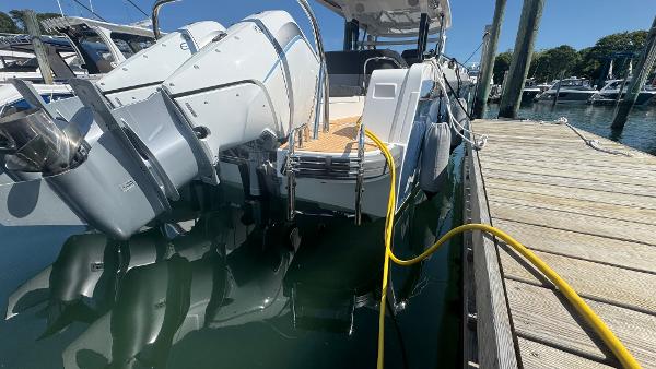2025 Nimbus T11 boat docked with dual outboard motors and yellow power cable.