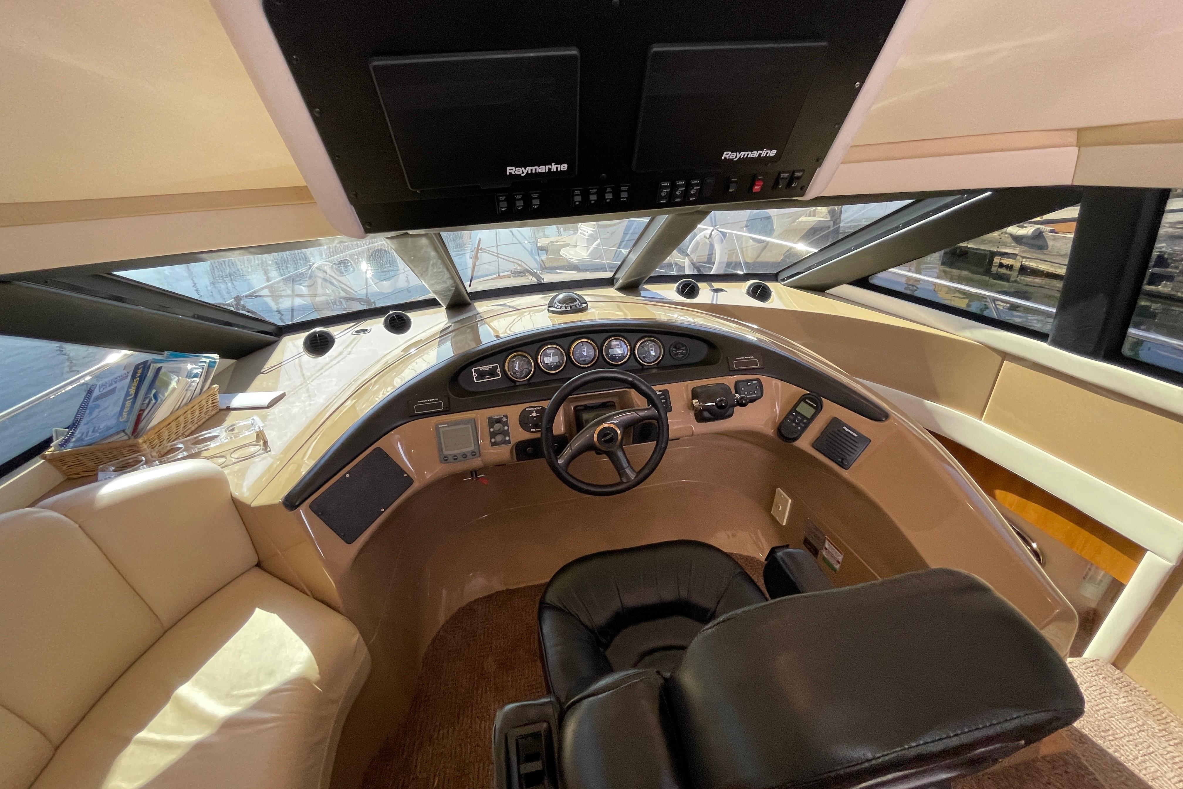 Pilothouse interior of 2002 Carver 570 Voyager, featuring steering wheel and navigation equipment.