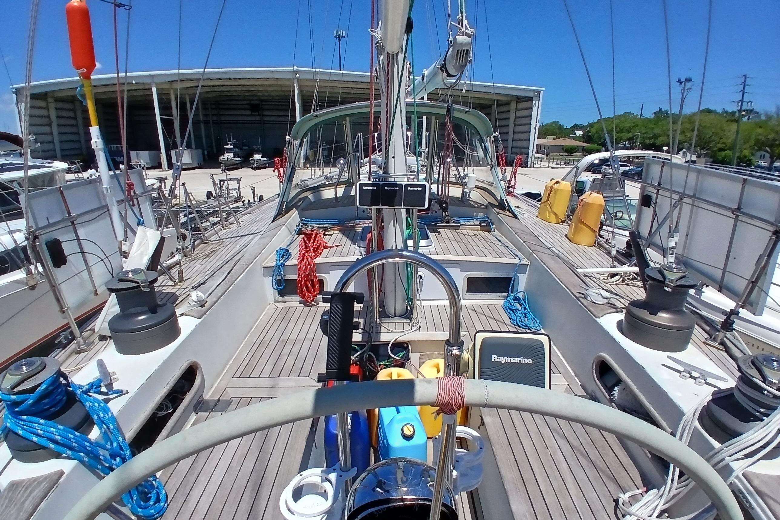 1981 Kaufman Skye 51 sailboat deck with equipment and ropes, docked near a storage facility.
