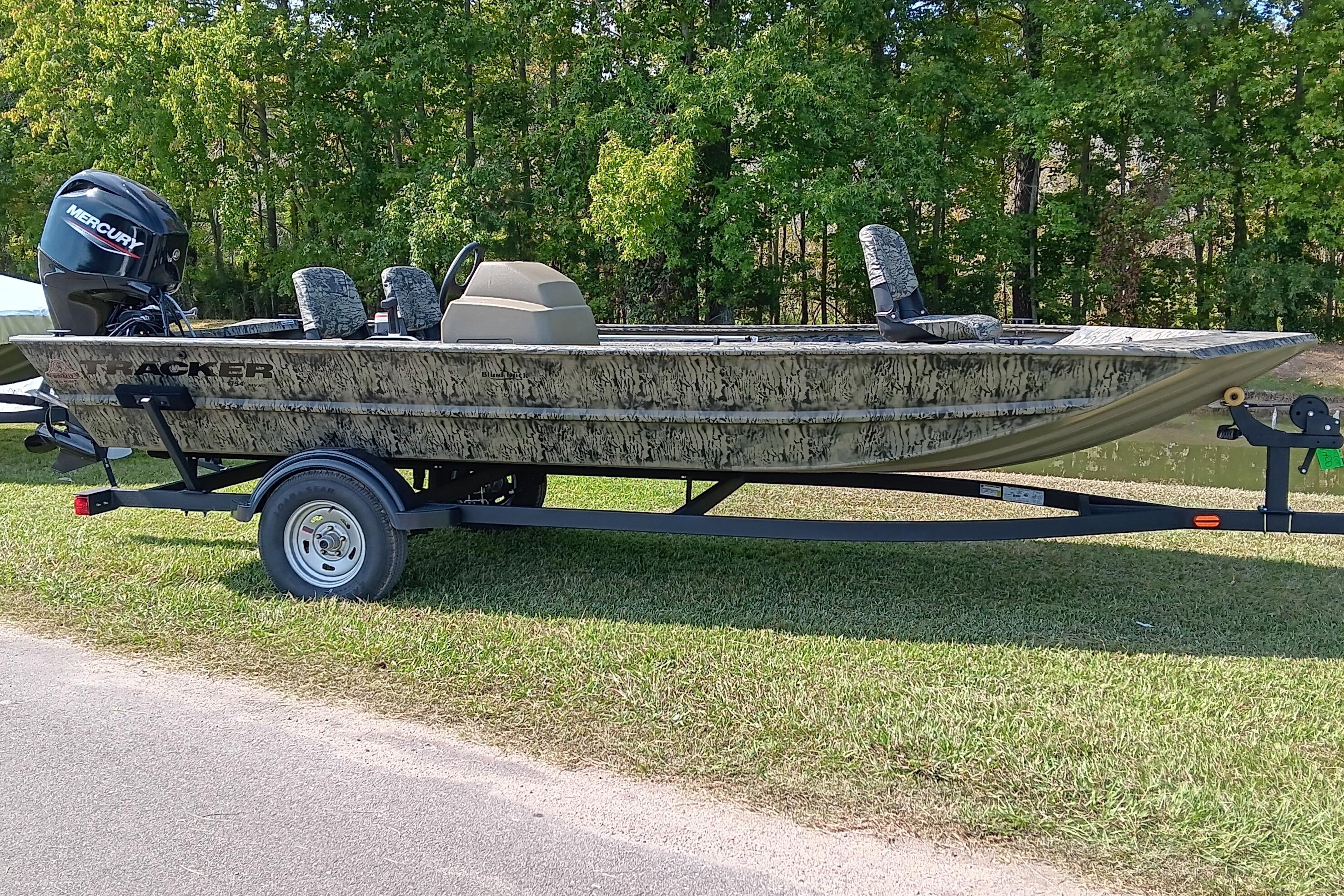 2026 Tracker Grizzly 1754 SC boat on trailer, camo design, parked on grass.