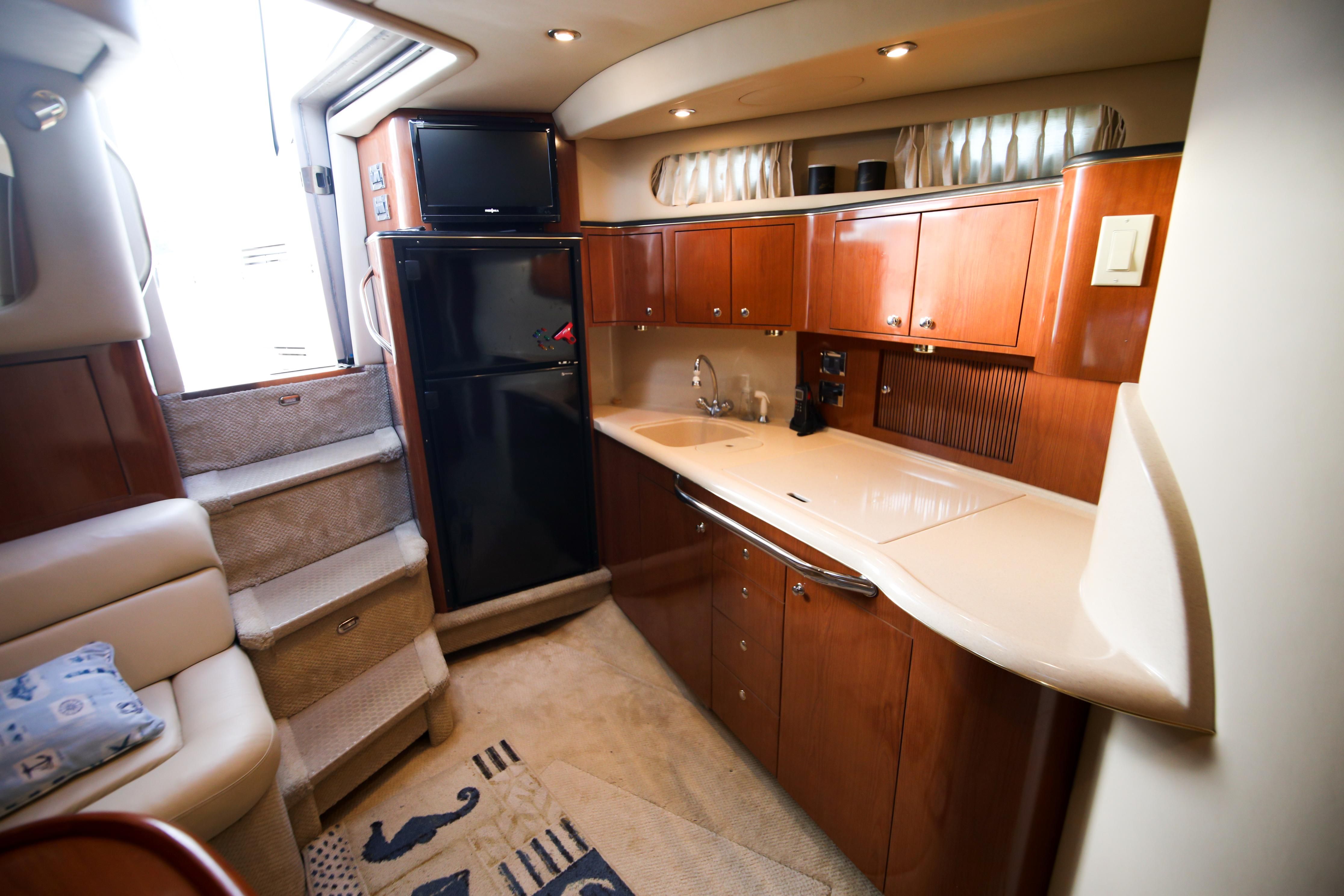 The 2002 Sea Ray 410 Express Cruiser's galley features elegant wood cabinets and modern appliances.