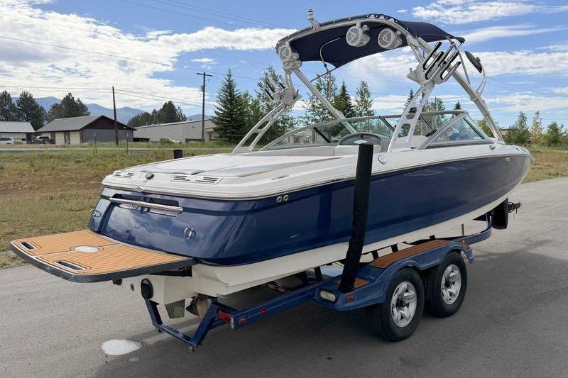 2004 MasterCraft XStar boat on trailer, blue and white, parked outdoors.
