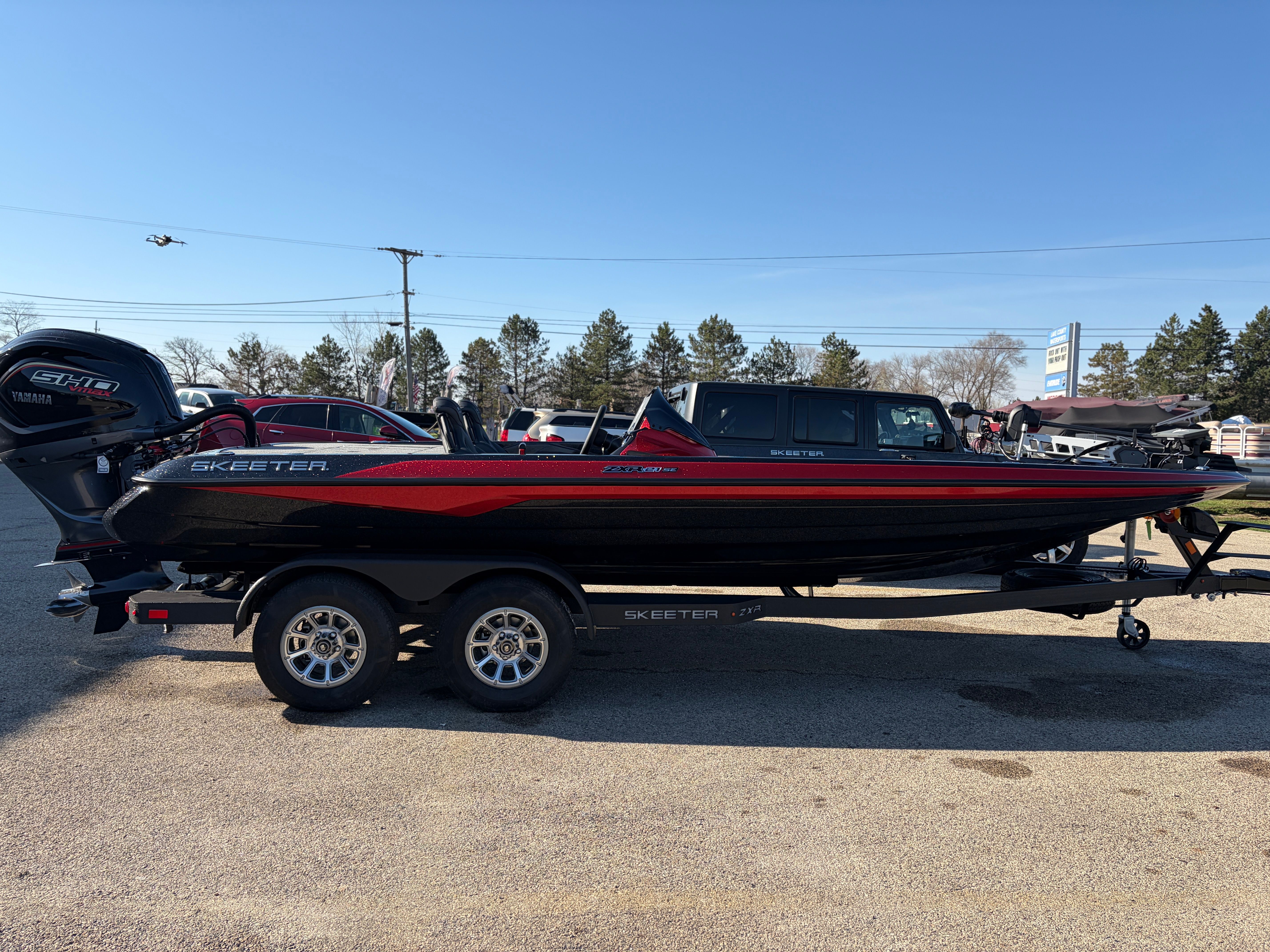 A black and red Skeeter ZXR21 SE boat on a trailer, parked in a lot.