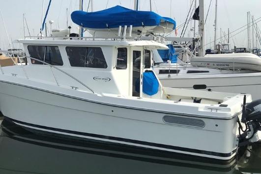 2005 Ocean Sport 30' boat docked in marina, featuring blue canopy and sleek design.