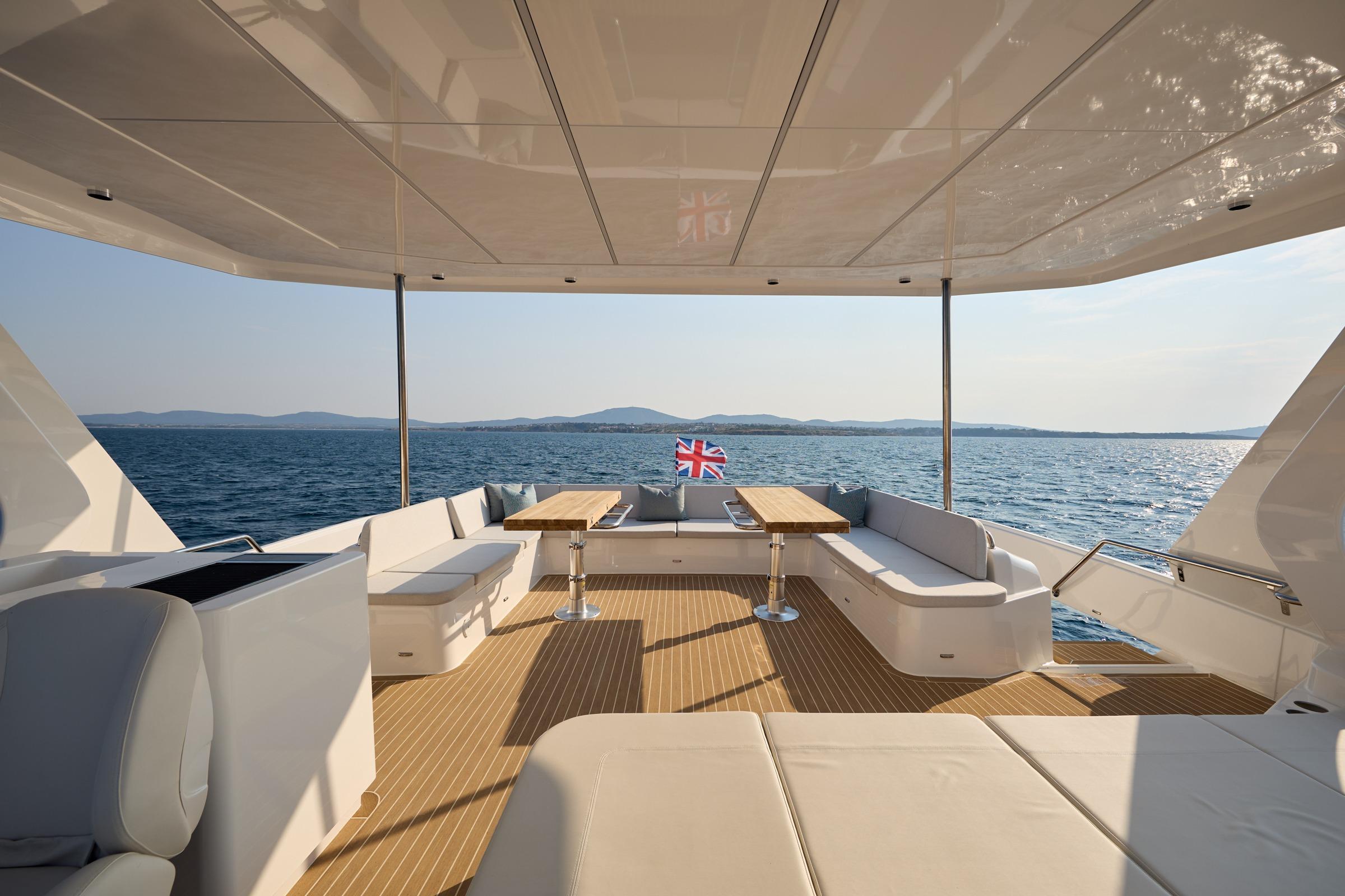 Luxurious 2025 Omaya 50 Power Catamaran deck with seating, ocean view, and British flag.