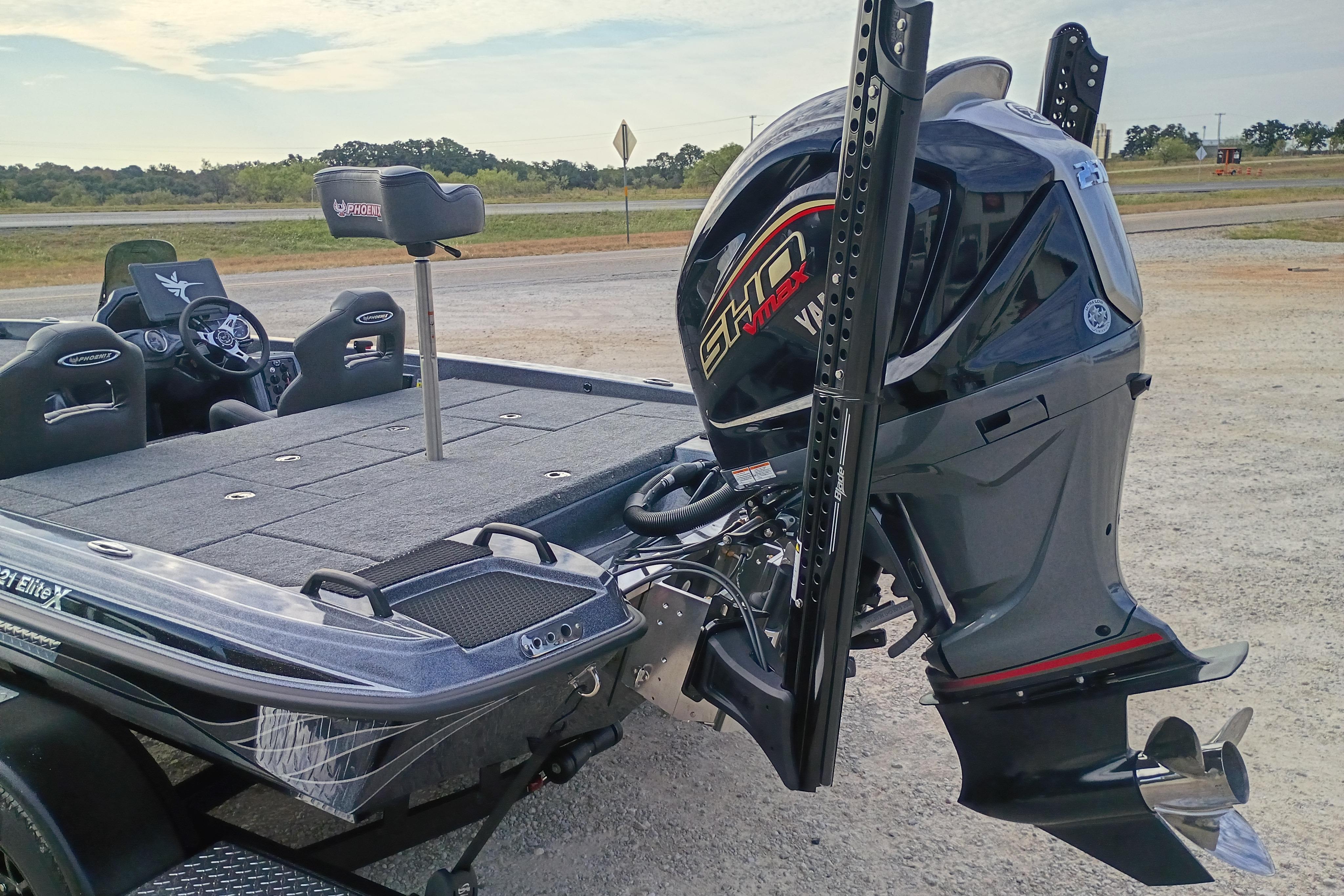 2026 Phoenix 921 ELITEX boat with powerful outboard motor, parked on gravel road.