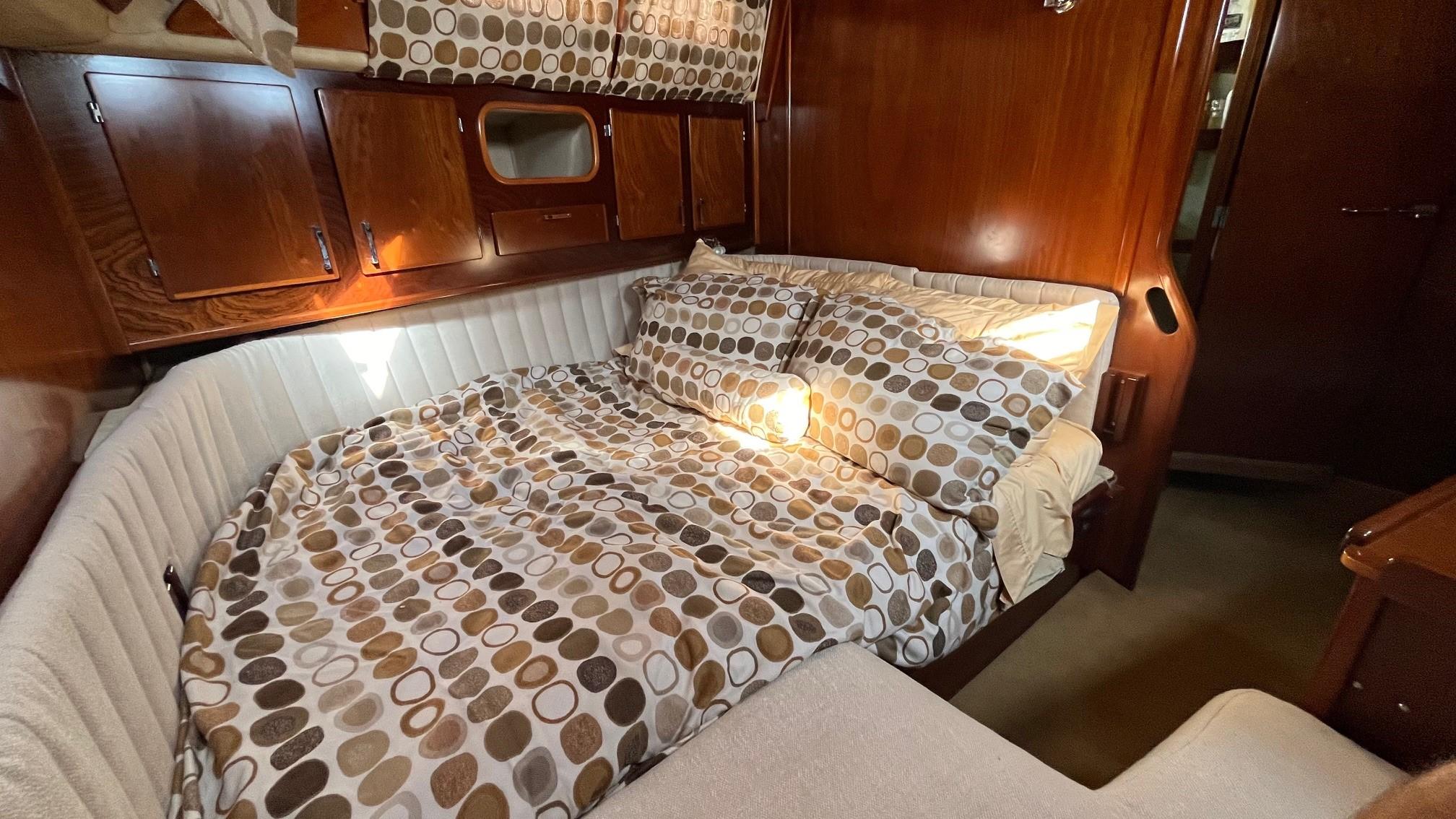 Cozy cabin interior of 1996 Amel Super Maramu-53 with patterned bedding and wooden accents.