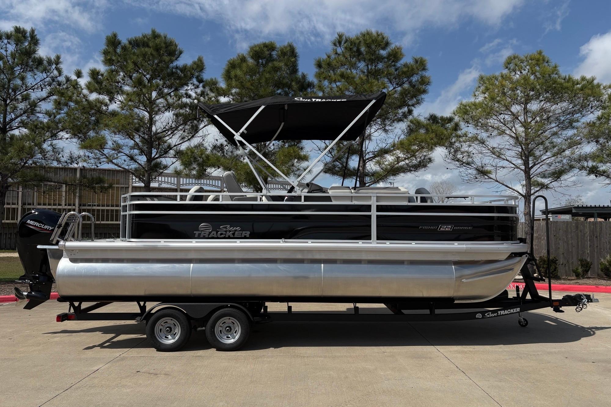2026 Sun Tracker Fishin' Barge 22 XP3 pontoon boat on trailer, parked outdoors.