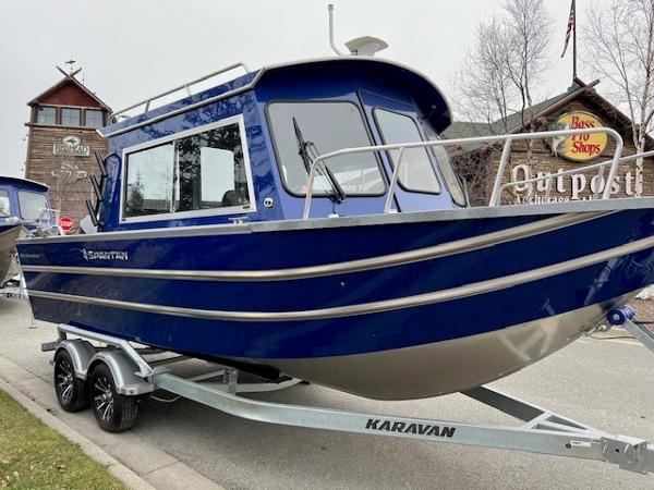 2023 Spartan 220 Maximus Pro boat on Karavan trailer, parked near a rustic building.