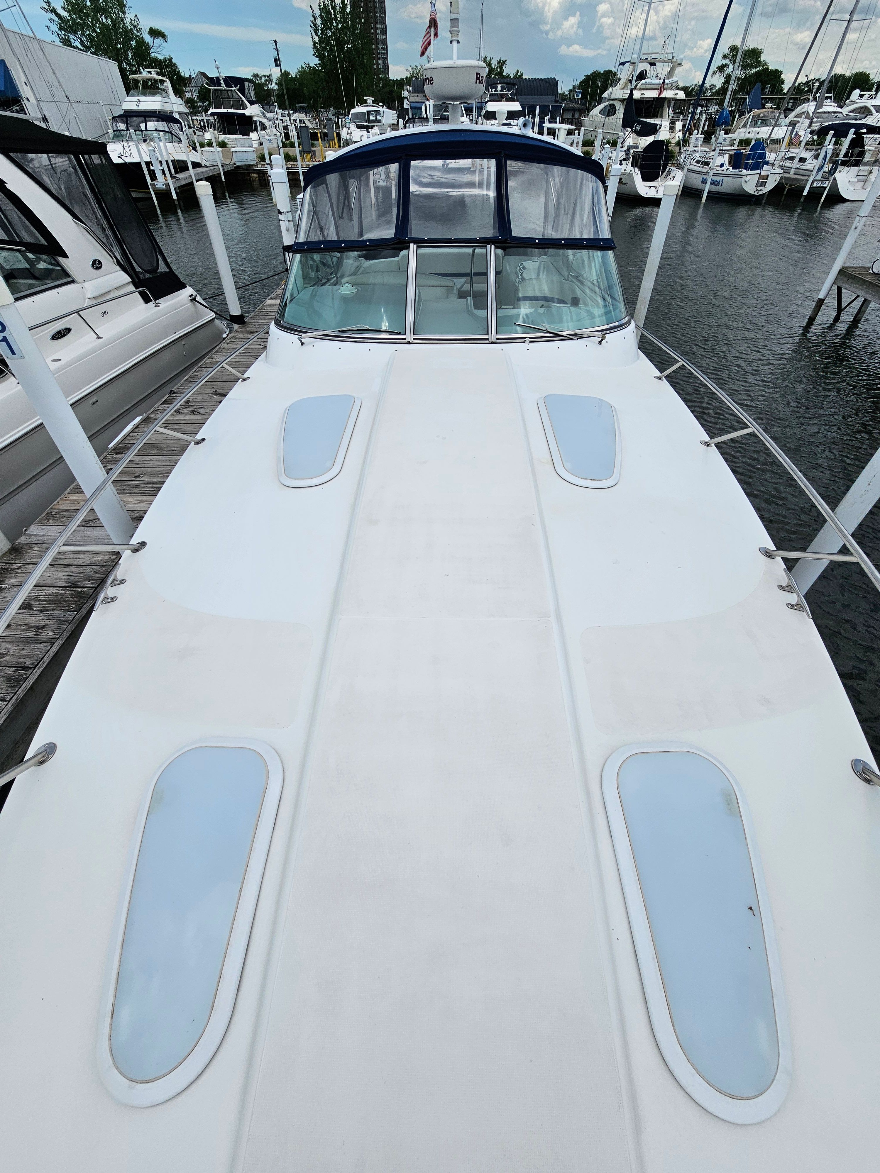 A white motor yacht docked in a marina, surrounded by other boats.