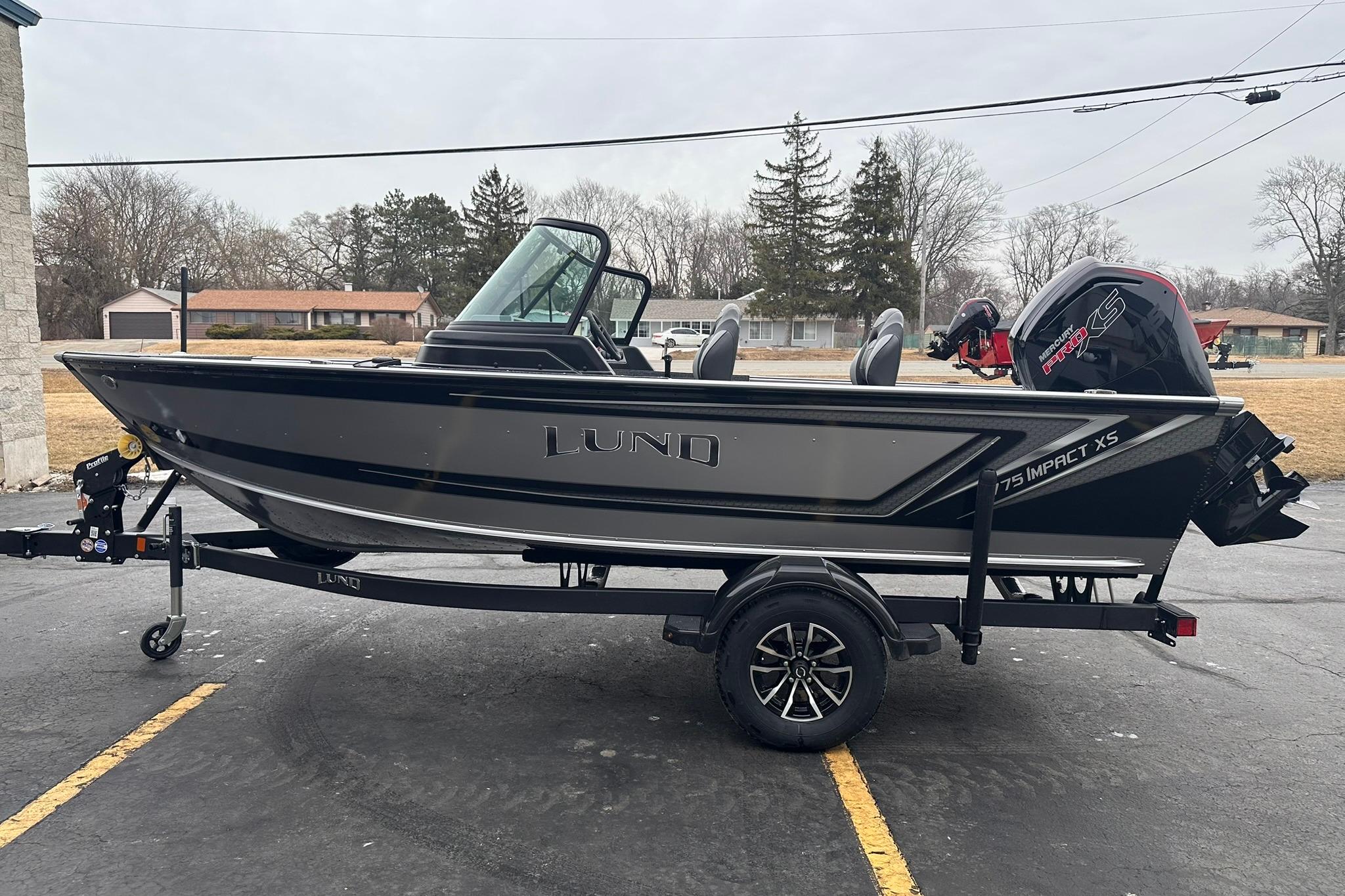 2026 Lund 1775 Impact XS Sport boat on trailer, parked outdoors.